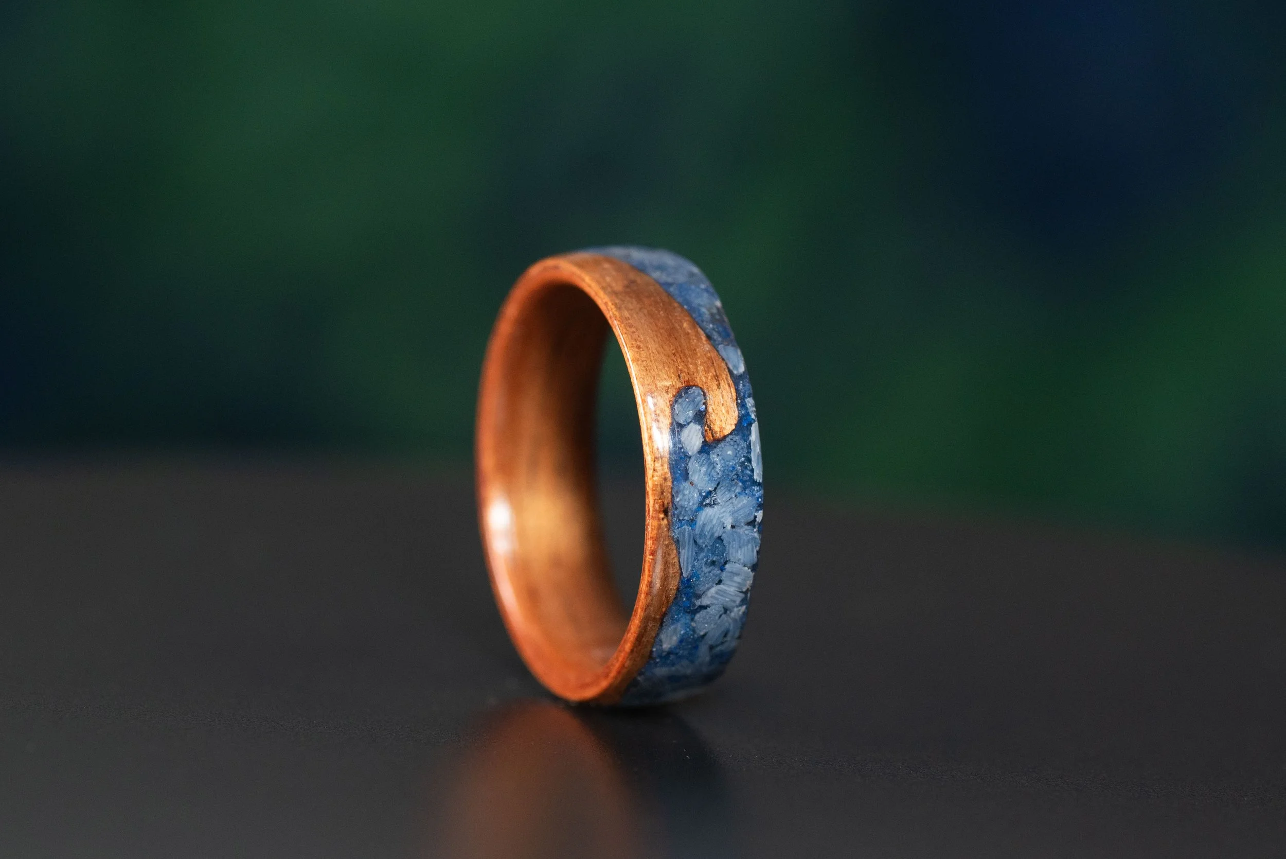 Handmade beach wedding band with koa wood wave and blue gemstone coastal inlay.