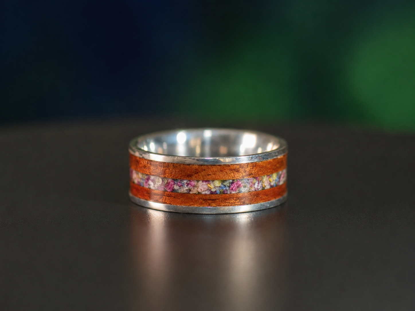 Custom 8mm sterling silver and mahogany keepsake ring with a colorful flower inlay made from customer-supplied petals.