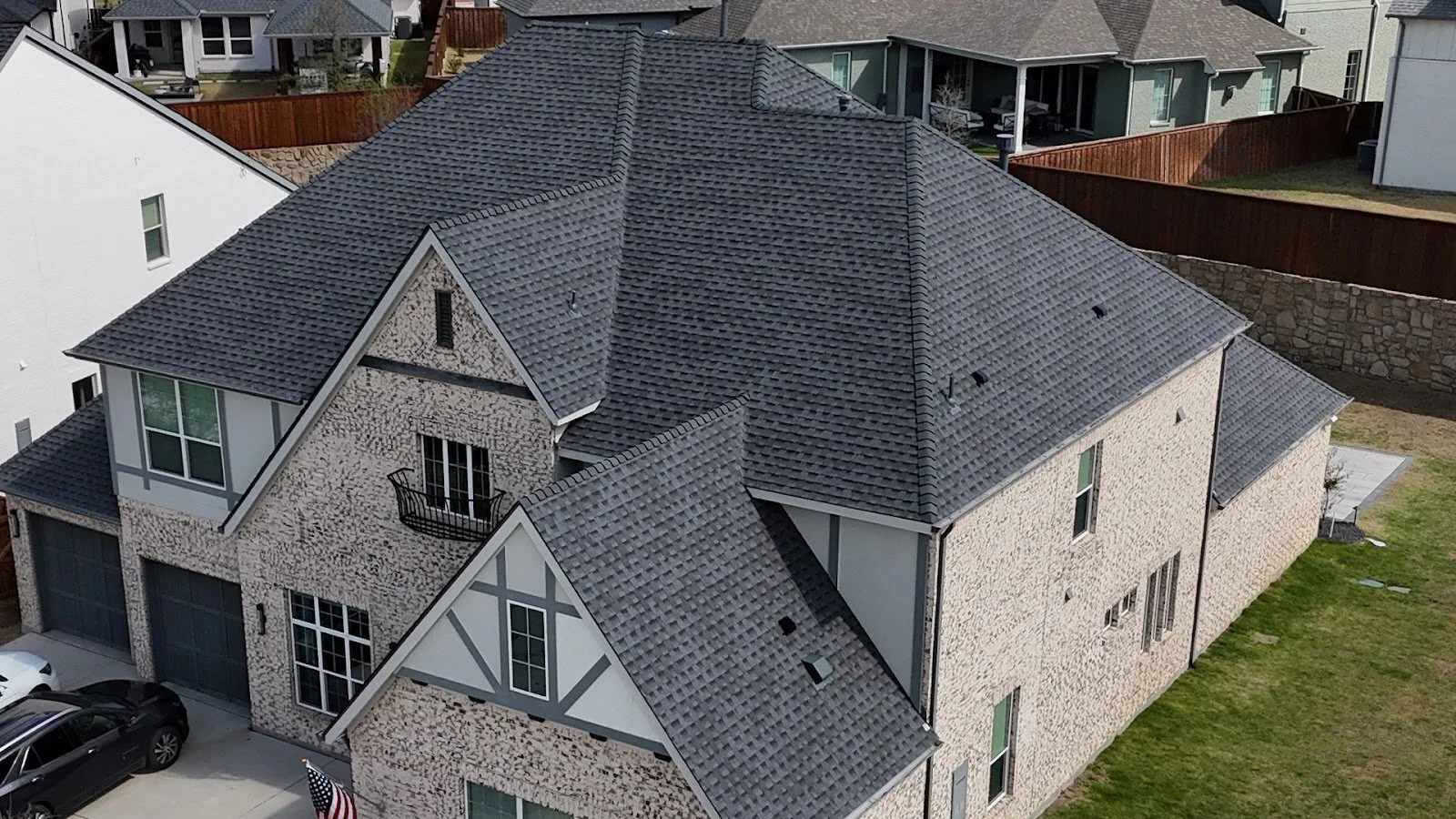 Aerial view of a two-story brick home with a gray asphalt shingle roof, the kind of roof to check after a hailstorm