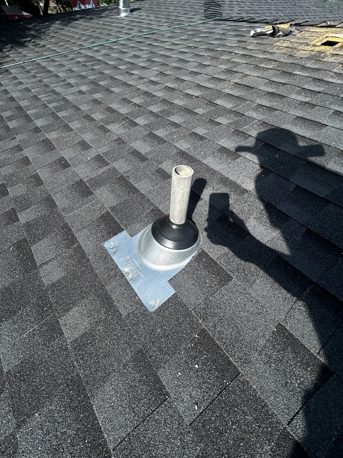 New pipe boot sealed around a plumbing vent on a dark asphalt shingle roof during a roof leak repair