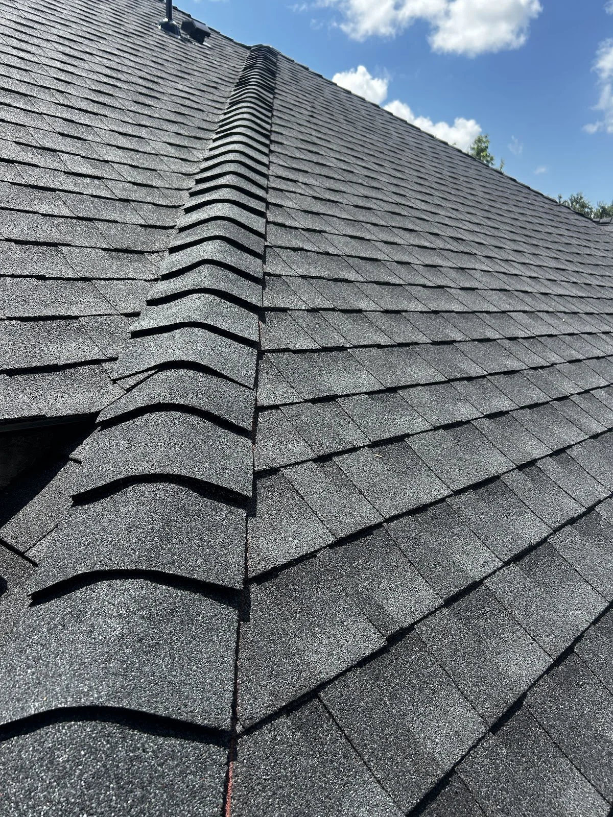 Close-up of a gray architectural shingle roof with ridge cap shingles on a finished roof replacement
