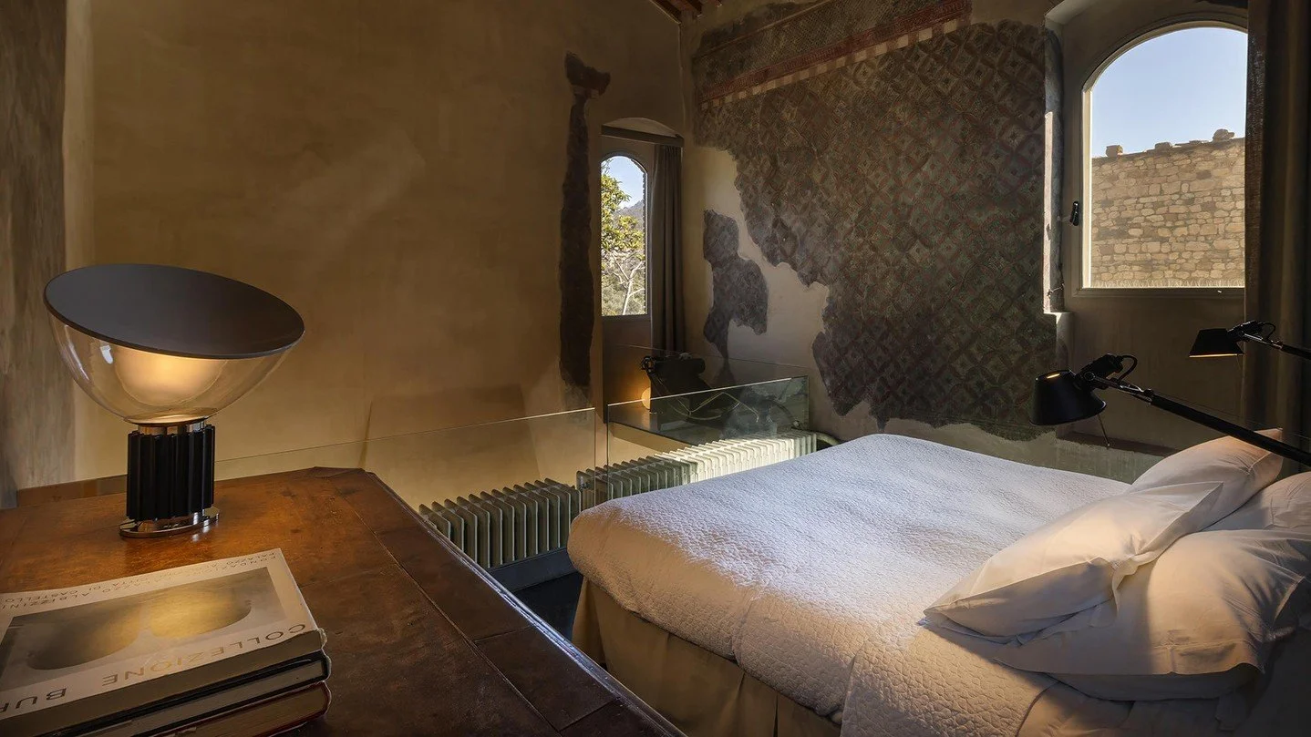 Soft light, timeless frescoes, and a calm that feels almost sacred.⁠
⁠
The Peruzzi Bedroom at Torre di Sopra blends 14th-century artistry with modern design classics, from the Taccia lamp by @flos to the Tolomeo by @artemide_lighting , the LC1 chair,