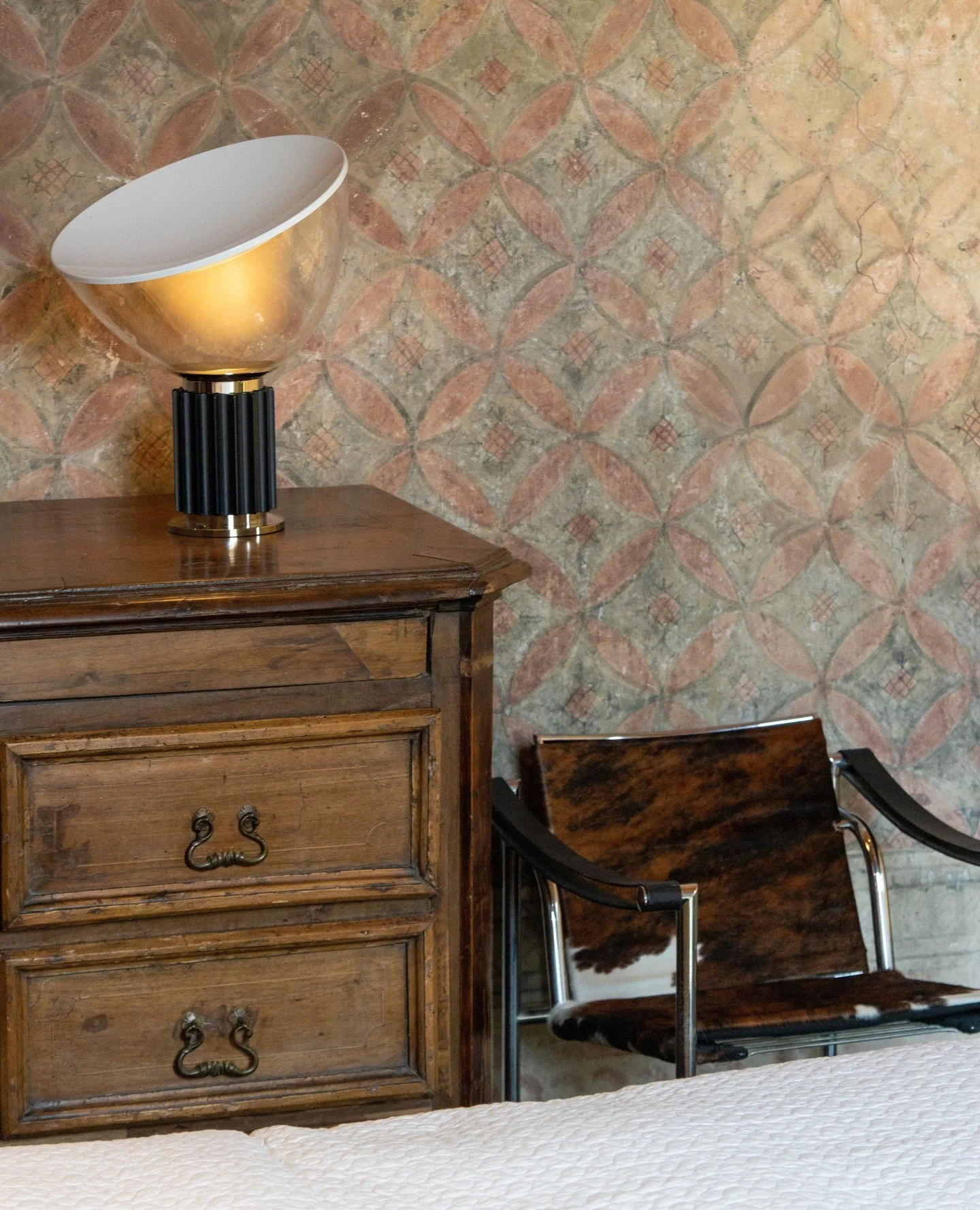 A room where time seems to soften.⁠
⁠
In the Peruzzi Bedroom, ancient frescoes watch quietly as the gentle glow of the Taccia lamp settles in, paired with the understated elegance of the LC1 Chair.⁠
⁠
History, light, and design come together to creat