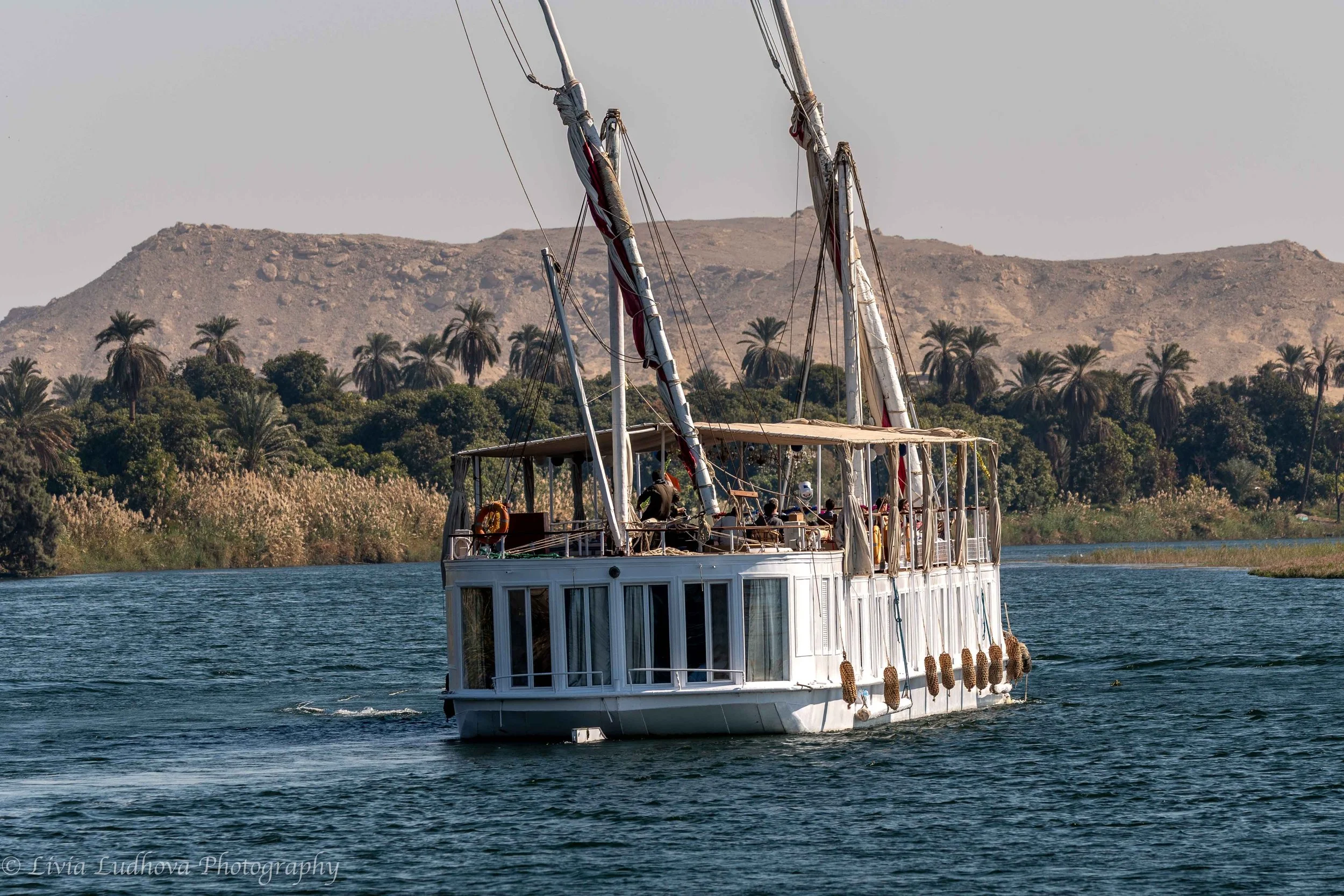 Dahabiya under sail, Nile — traditional river navigation against a desert backdrop.