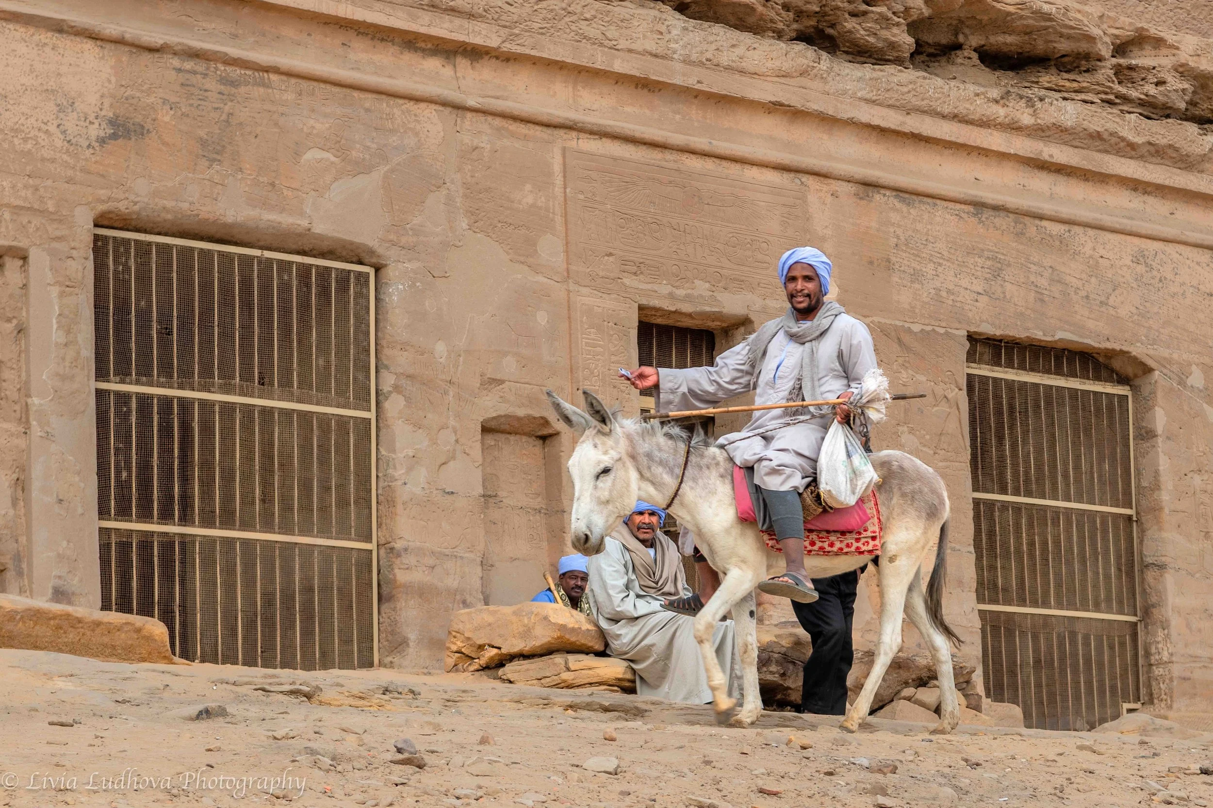 Local worker arriving to  work, in front of a small building protecting rock-cut burials close to the mooring point.