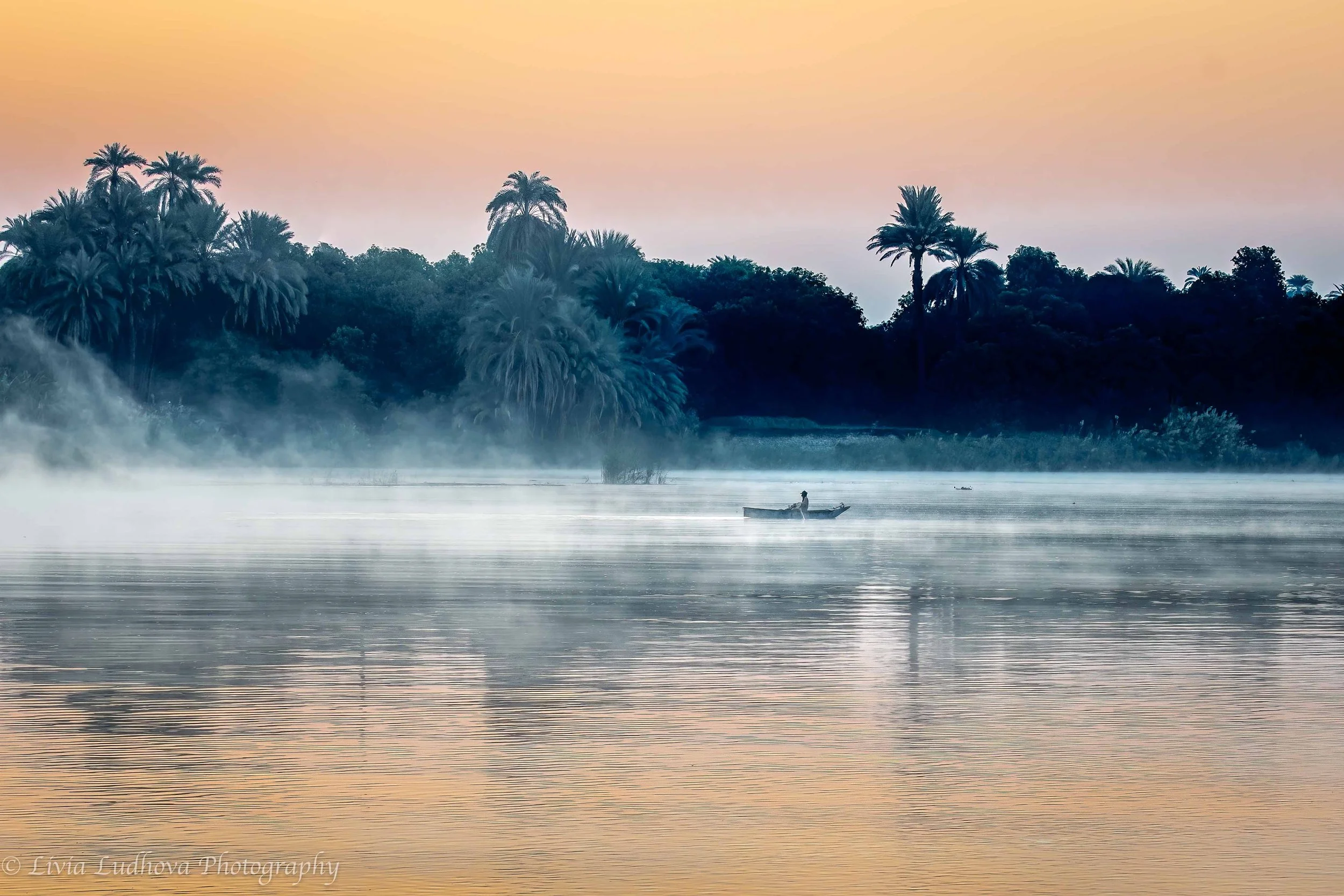 Calm sunrise with mist and small fisherman boat.