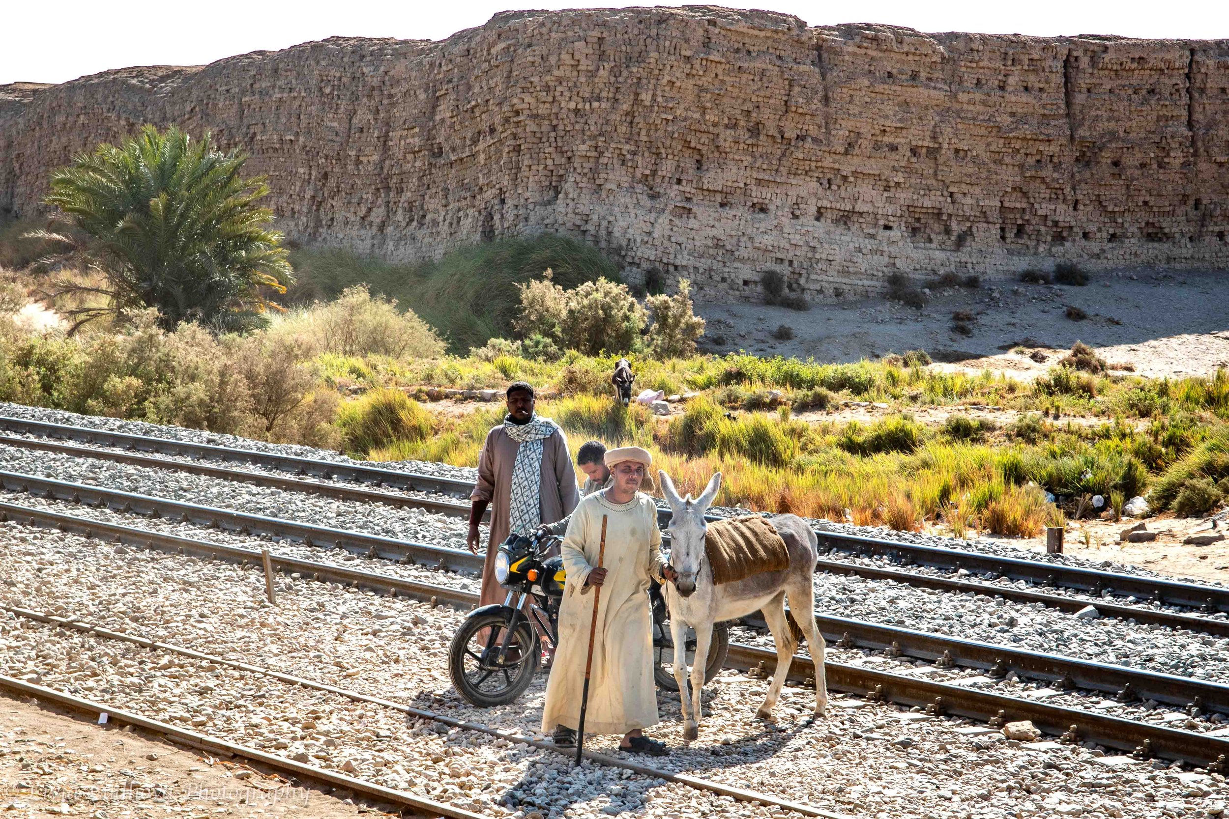 Locals with a donkey and motrbike  near the railway — everyday mobility along the Nile corridor.