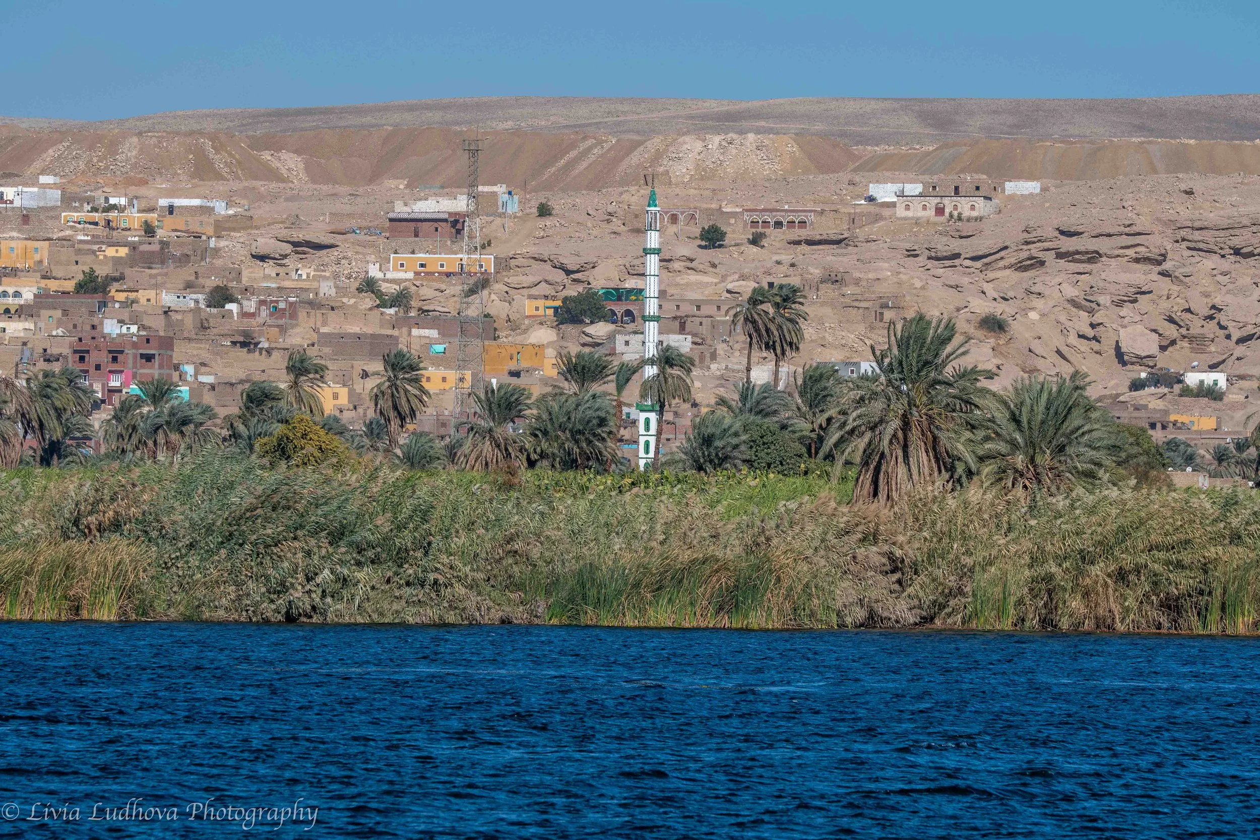 Village panorama across the river with white minaret.