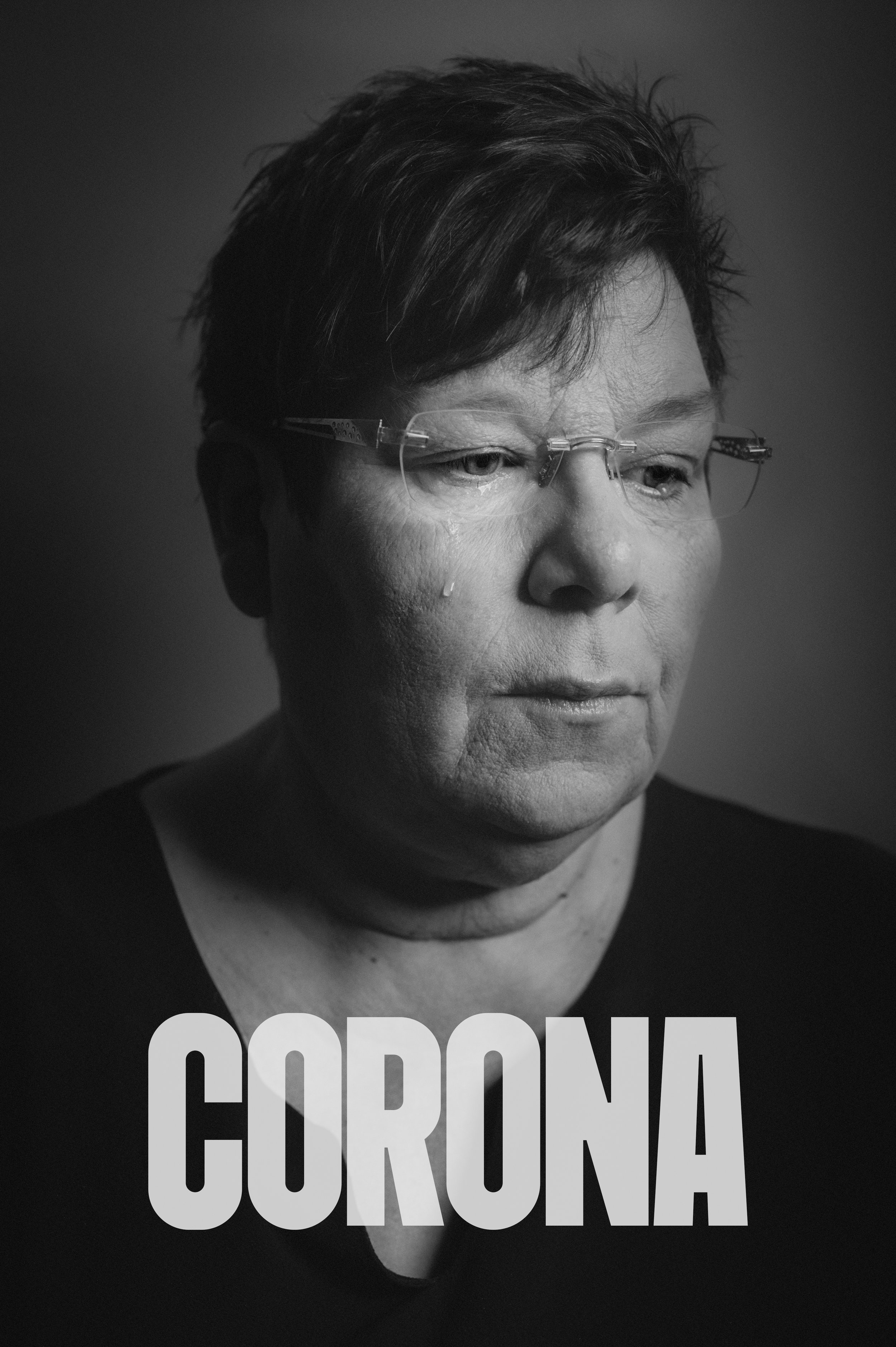 schwarz-weißer Portrait eines ernst schauenden Mannes mit Kurzhaarfrisur, der eine Brille trägt, mit dem Text "CORONA" am unteren Rand