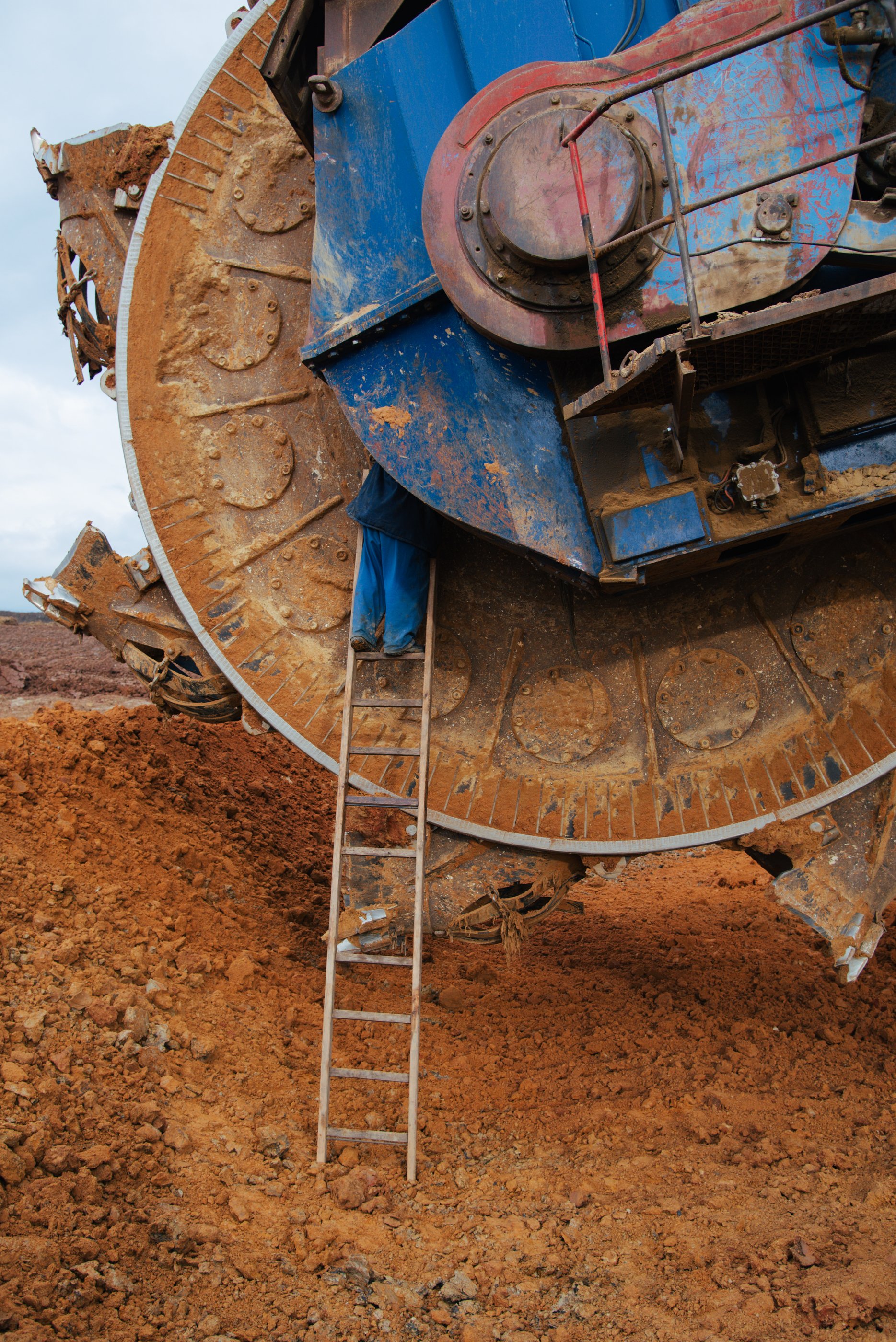 Ein großer Baggerschaufel, die auf einer Baustelle Erde schaufelt, mit einem Arbeiter, der eine Leiter hochklettert.
