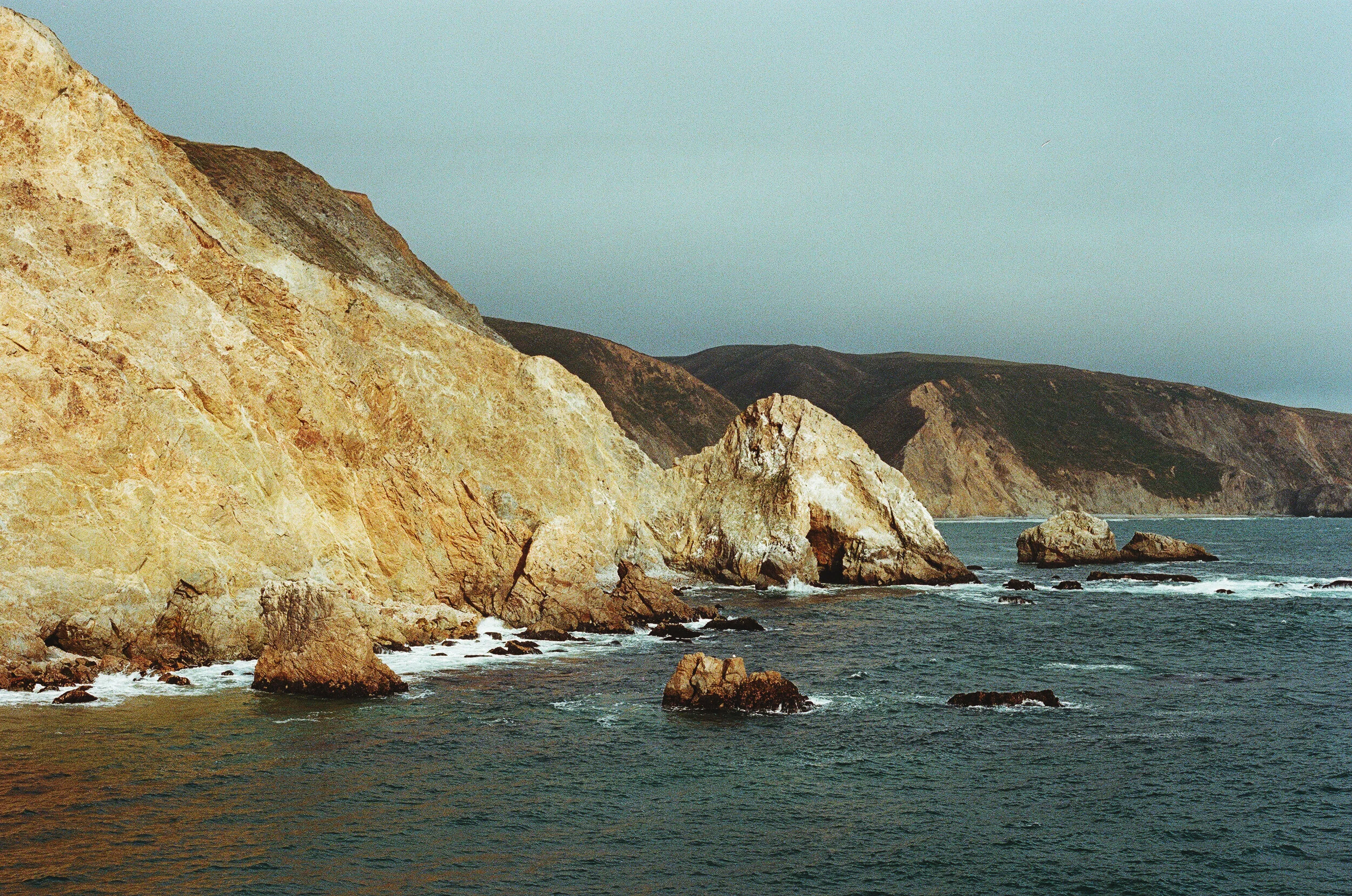 Sunlight breaks through the fog, bathing the cliffs in a warm glow.