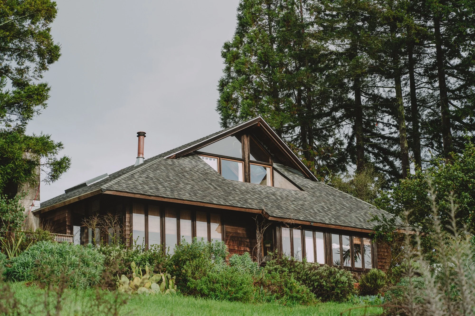 a large house with many west-facing windows sits atop a hill surrounded by greenery