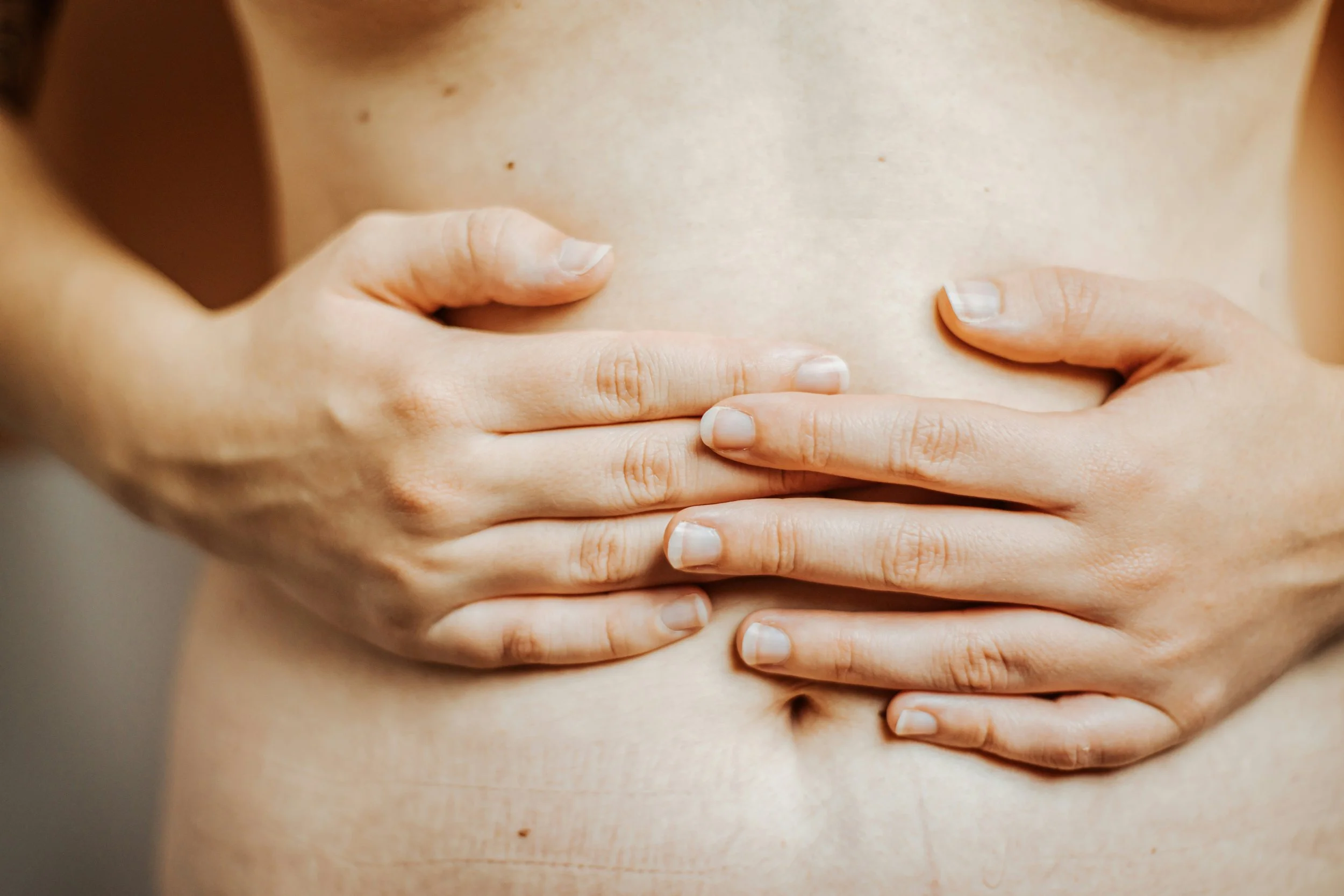 Close-up of a person with their hands on their belly.