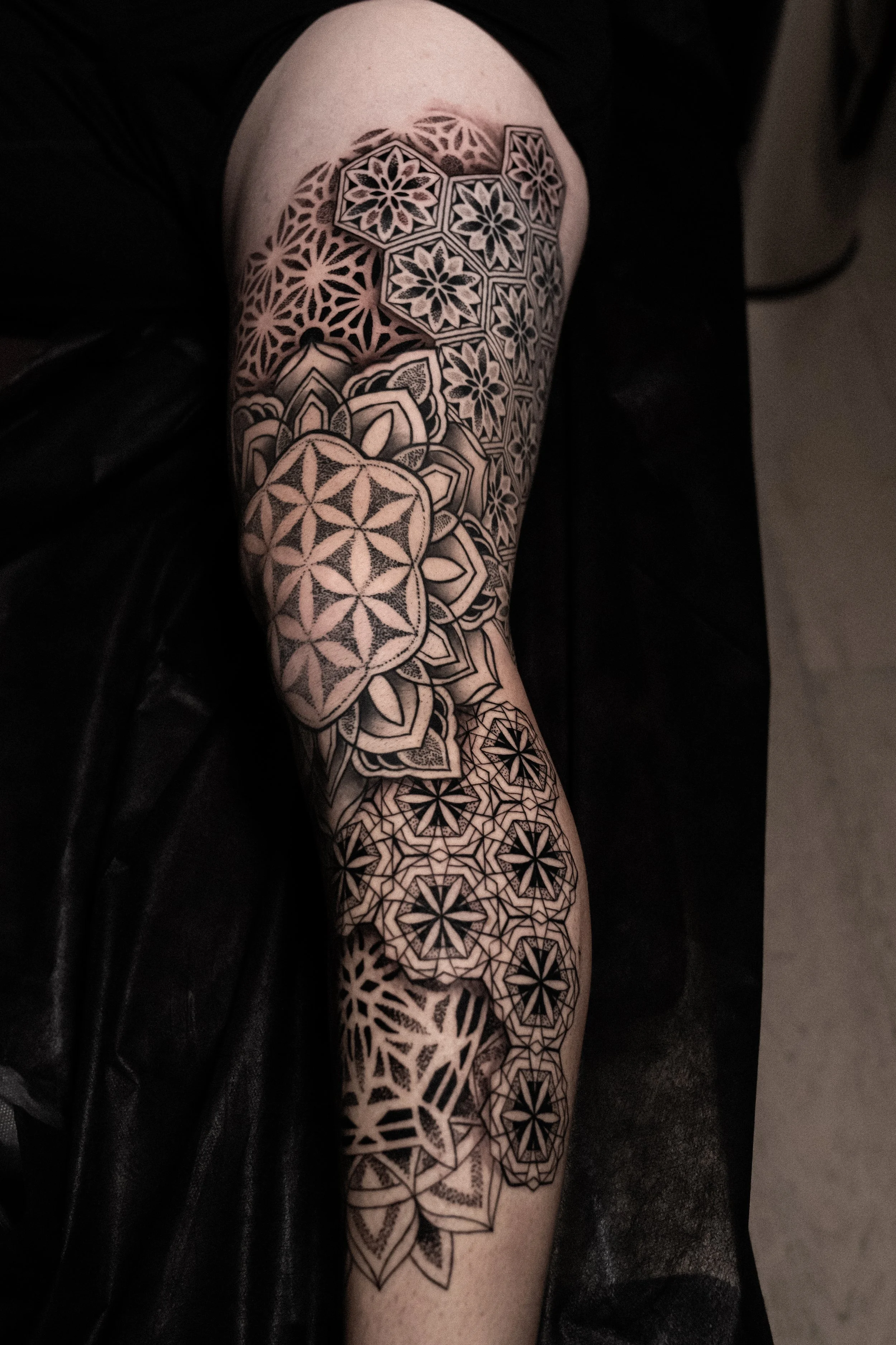 Black and gray geometric sleeve tattoo with floral patterns on arm.