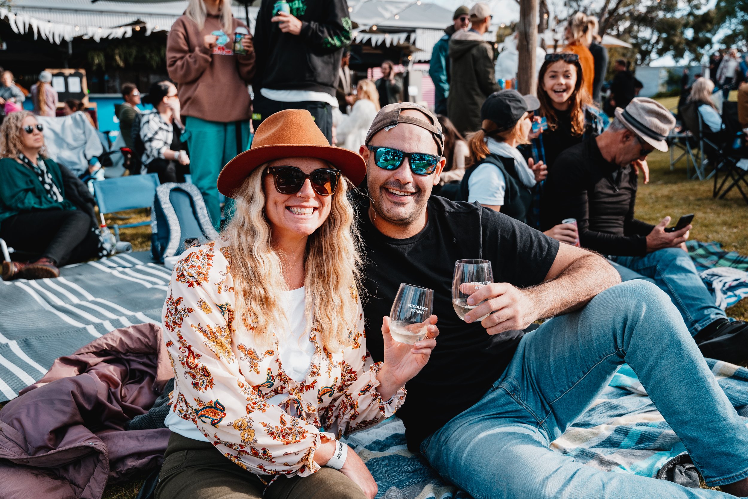 friends sitting on picnic rug & enjoying wine