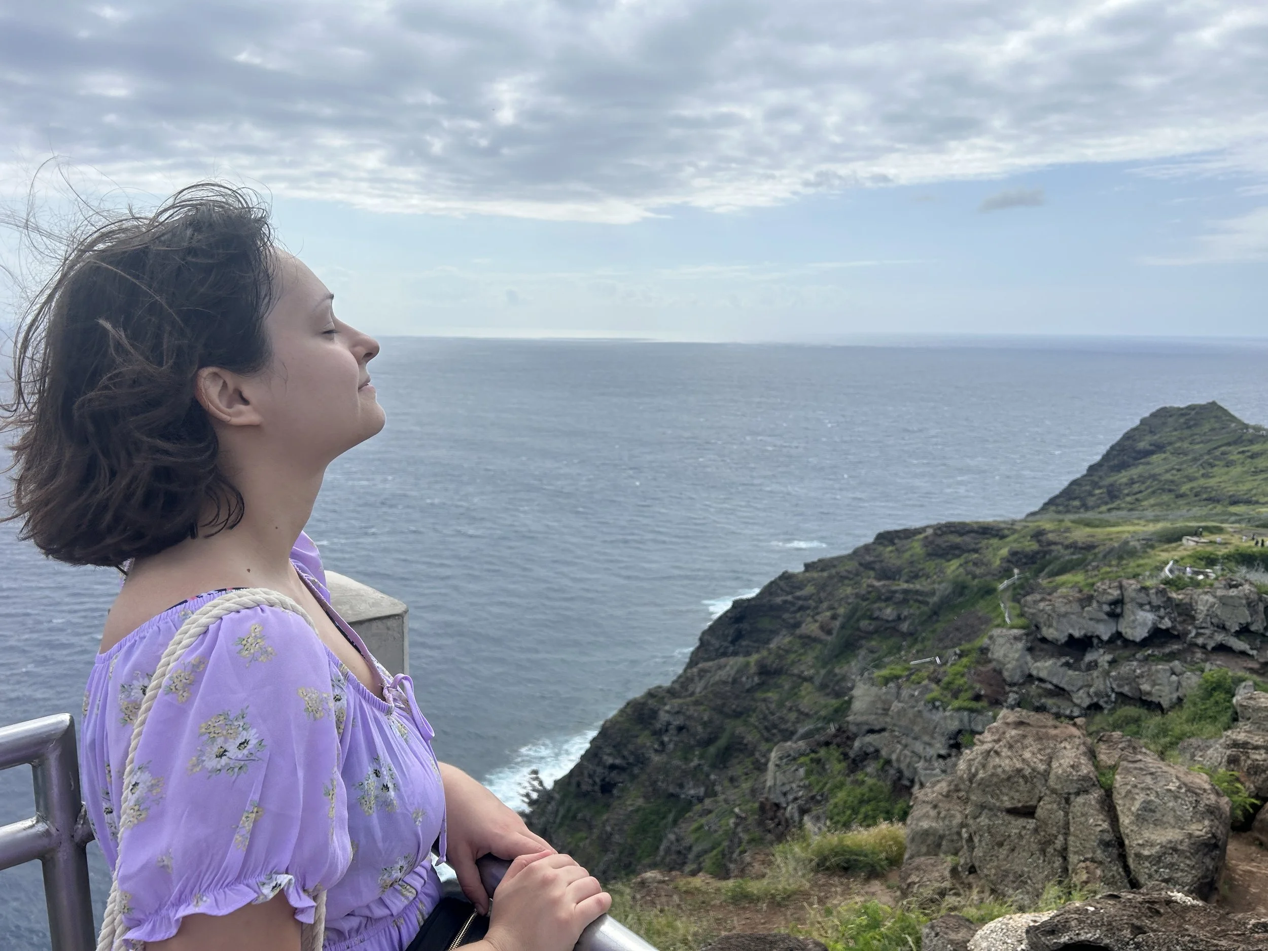A woman resting with her eyes closed by the ocean, representing calm and mental clarity