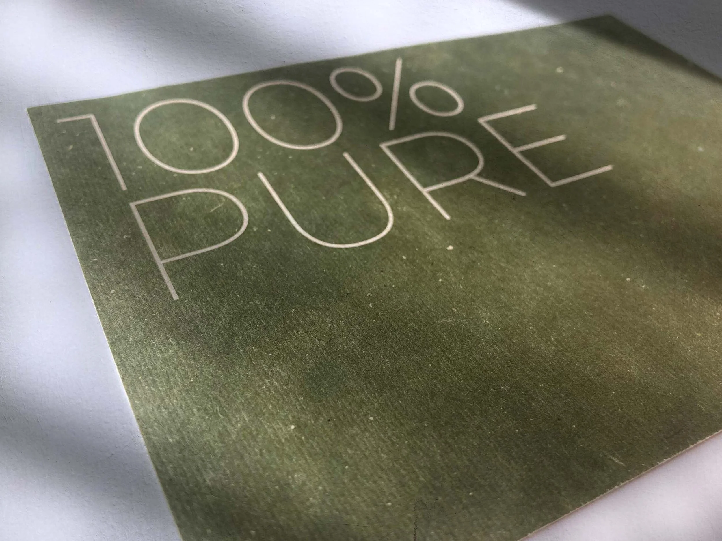 Grusskarte auf grünem Hanfpapier mit dem Schriftzug 100% PURE – Pure Materials