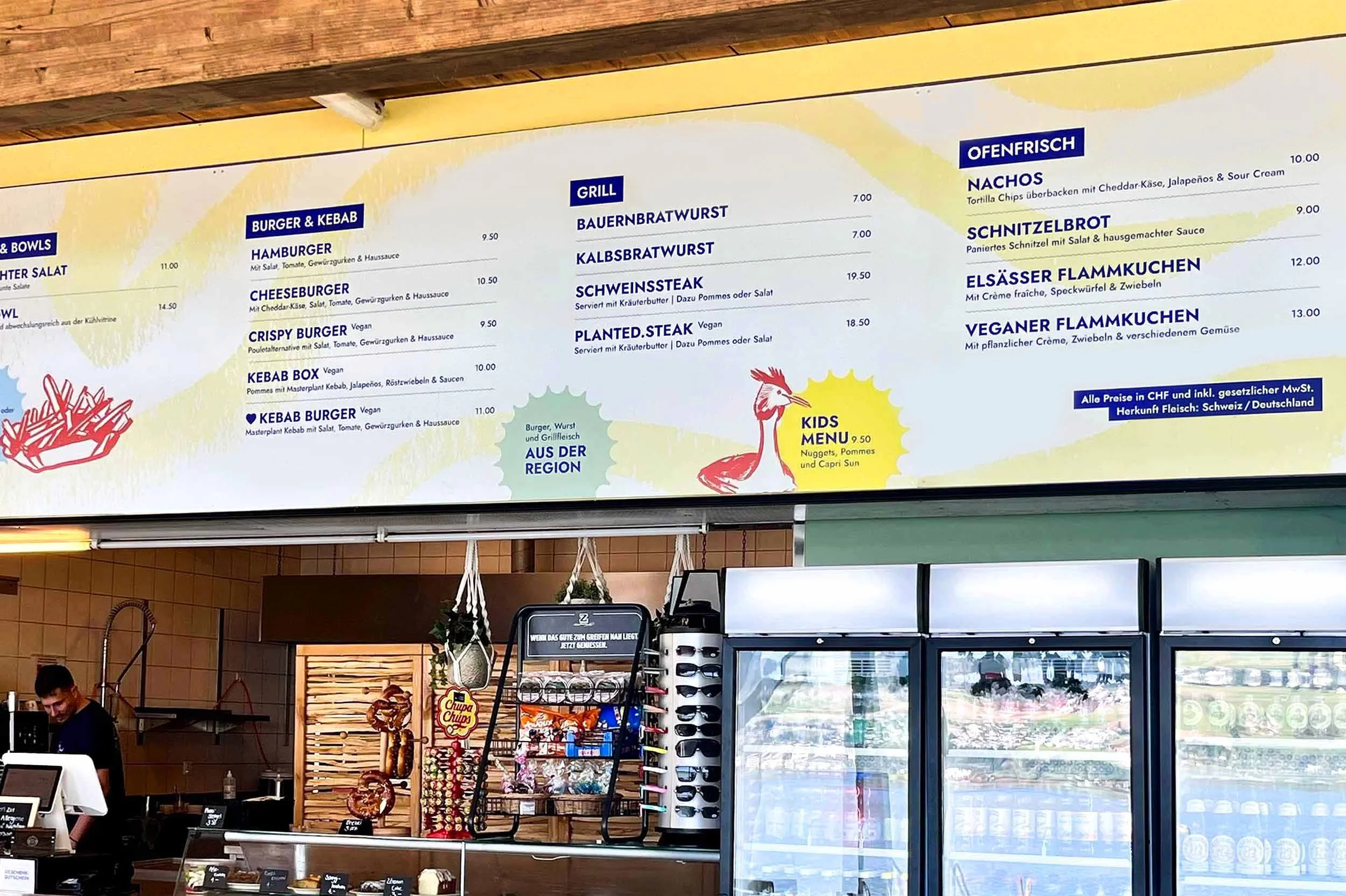 Beschriftete Info- und Menütafeln über dem Kiosk-Verkaufsfenster des Seebad Nottwil