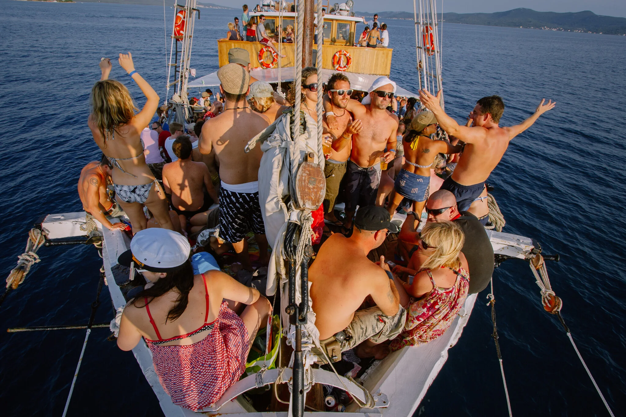 Menschen feiern und tanzen auf einem Boot auf dem Meer, bei sonnigem Wetter
