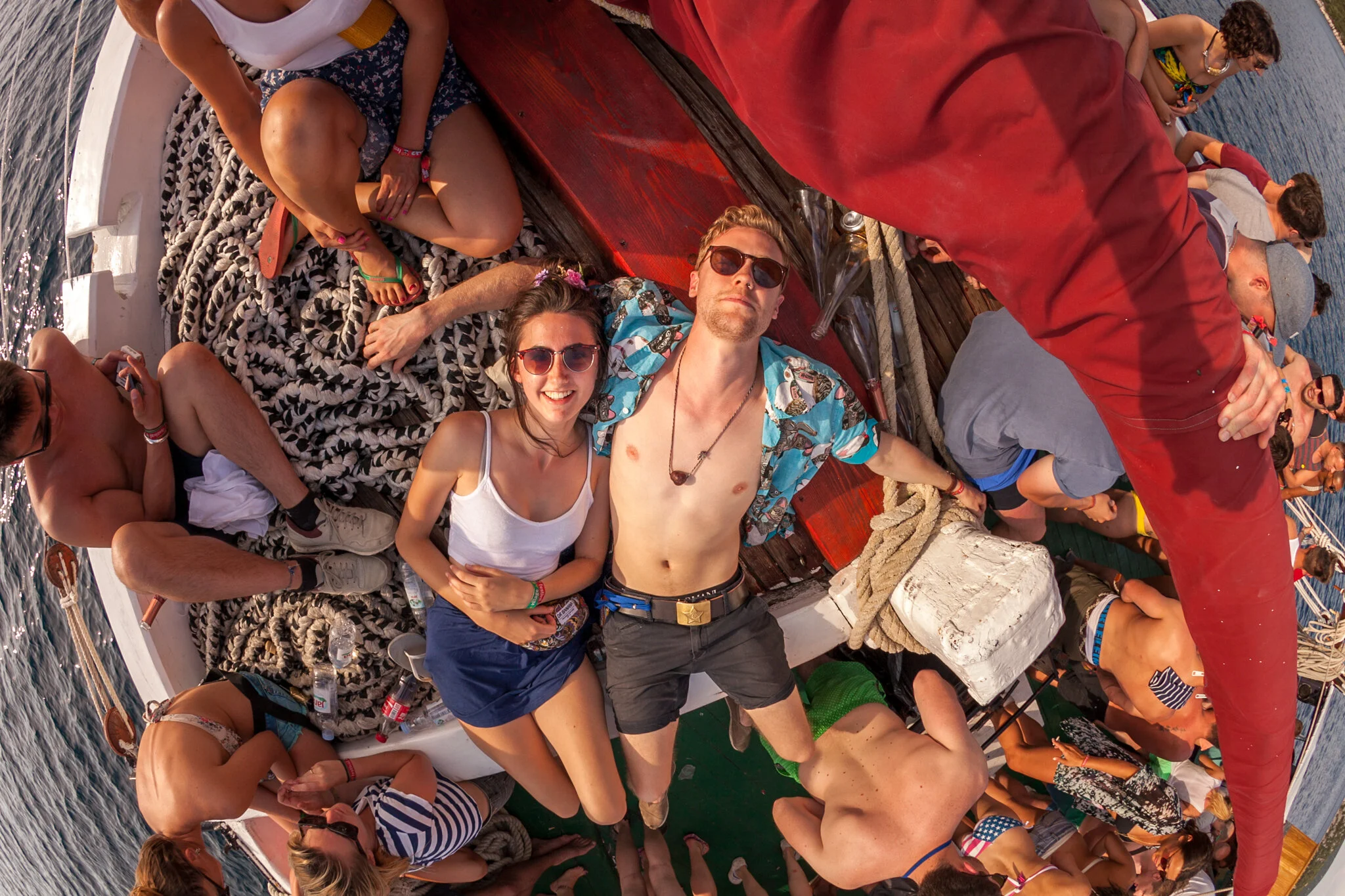 Menschen feiern auf einem Boot, einige liegen, andere sitzen, im Meer, sonnig, Sommer, Party, Freunde.