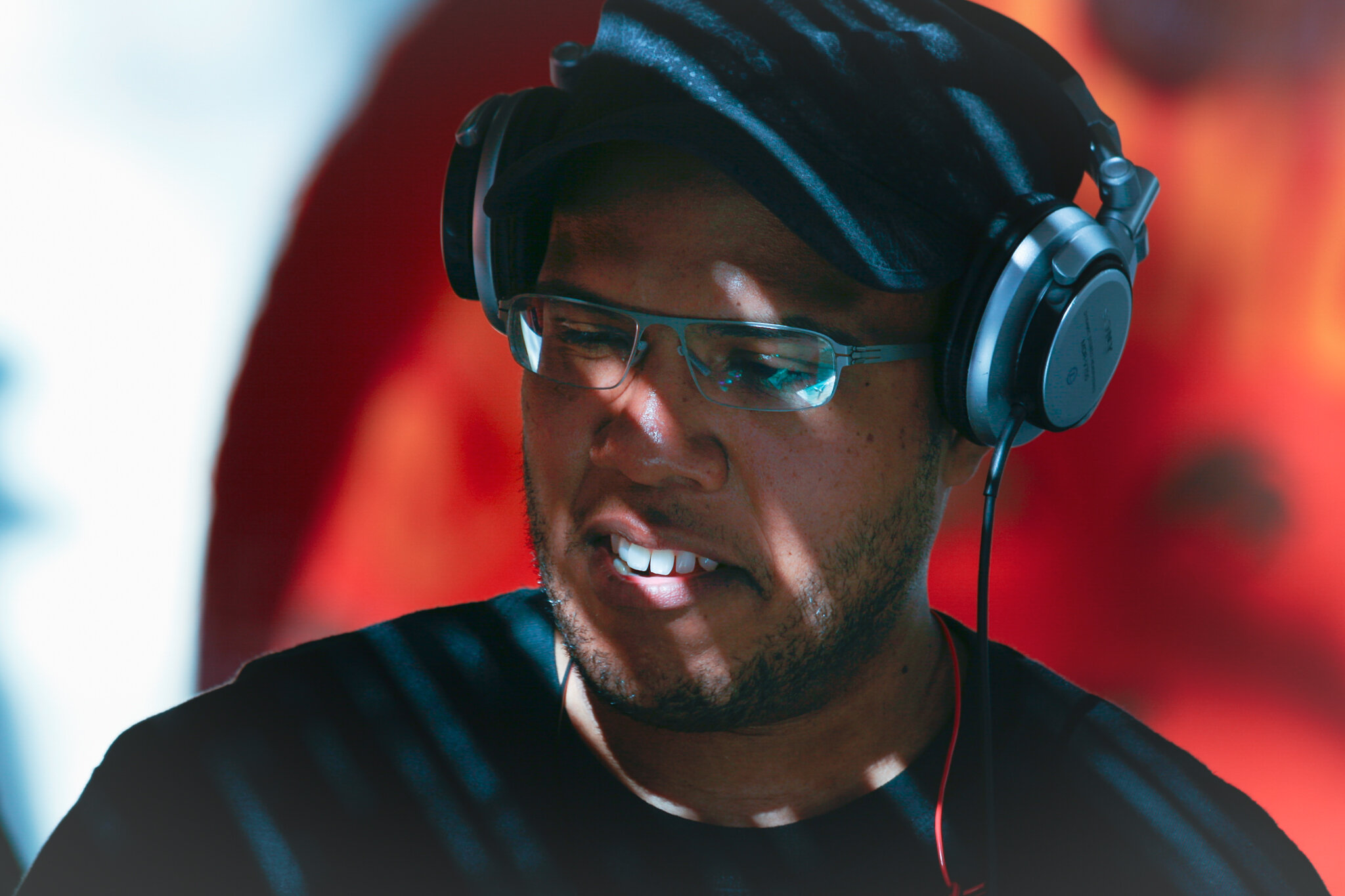 Junger Mann mit Brille und Kopfhörern, lachend.