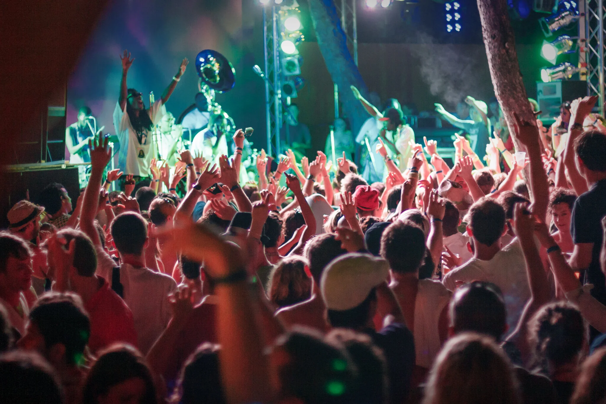 Menschen tanzen und feiern vor einer Live-Band auf einer Bühne bei einer Party