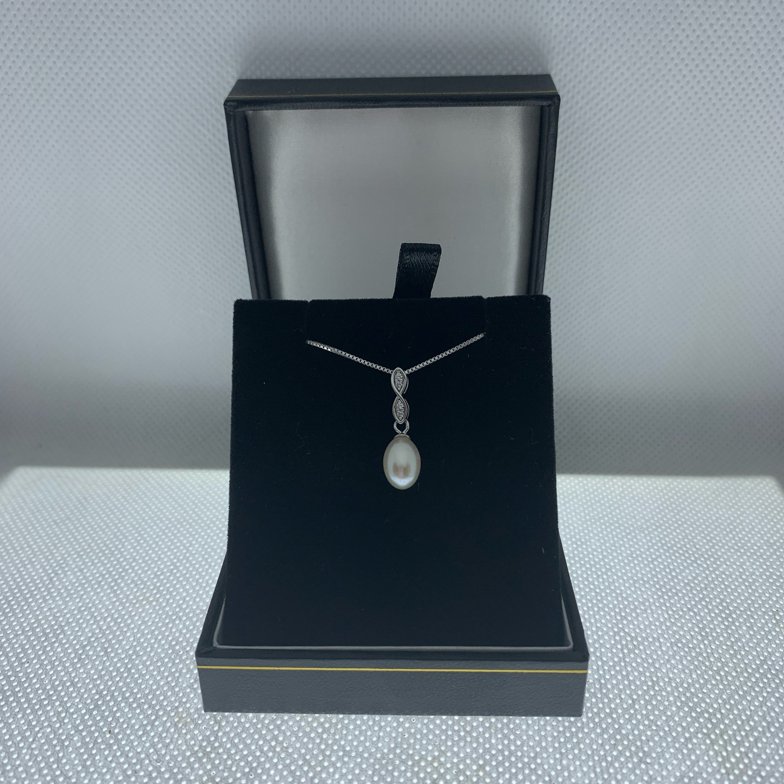sterling silver drop pendant with 9mm freshwater pearl suspended below two sparkling cubic zirconia on a silver s shaped drop on an 18 inch sterling silver chain presented in jewellers gift box