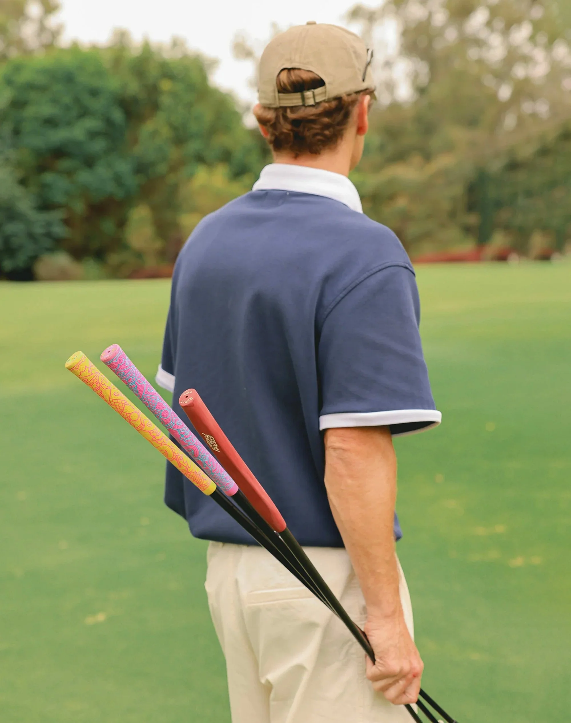 Rear view of a golfer on the course with a golf bag and clubs featuring Brosmind's custom rubber grips for RIPIT Grips.