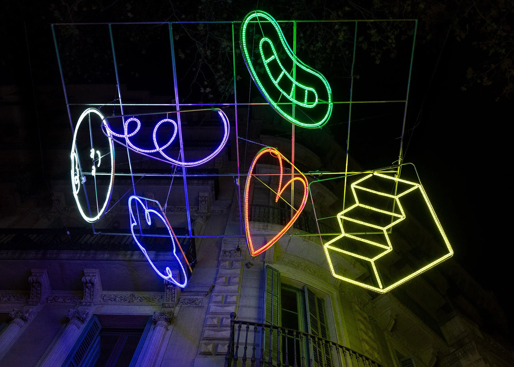 Low-angle night detail photo of a glowing multicolor icon cloud light installation by Brosmind.