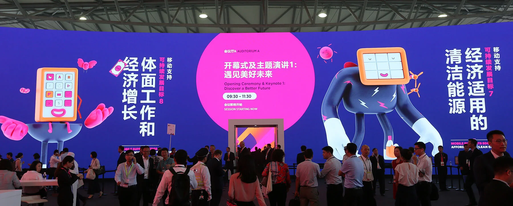 Large LED screen showing SDG character illustrations alongside event information at Mobile World Congress.