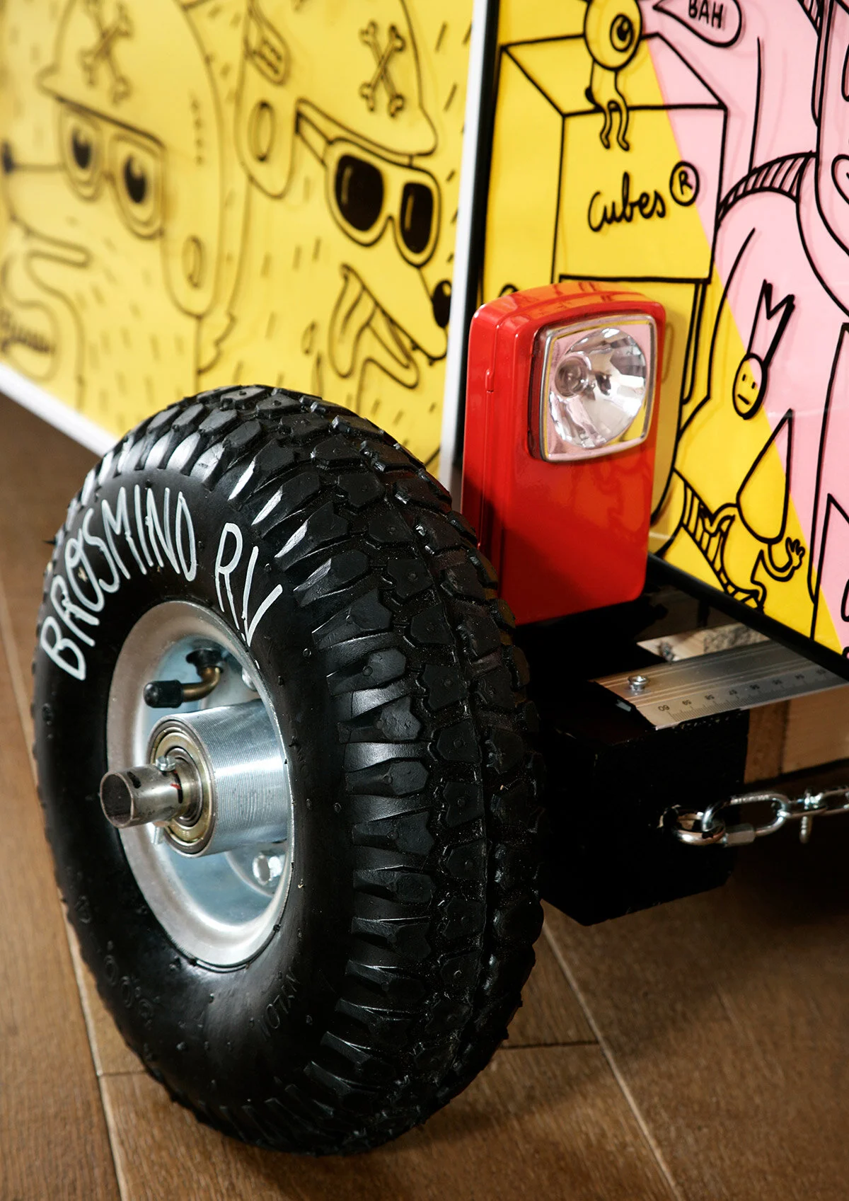 Close-up of the Brosmind RV front wheel with white logo branding and a vintage red flashlight headlight.