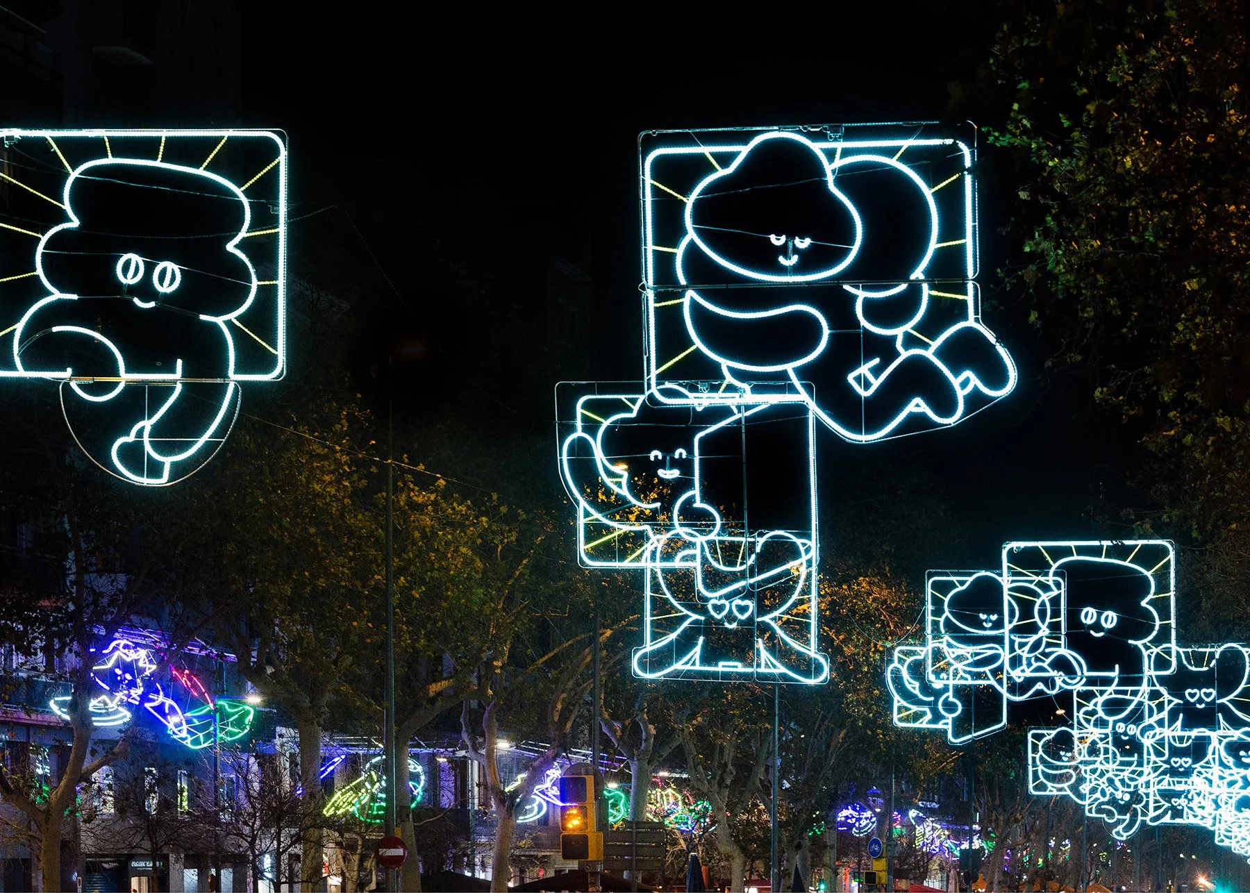 Close-up night shot of a light panel showing Kawaii characters hugging and holding glowing red hearts. 