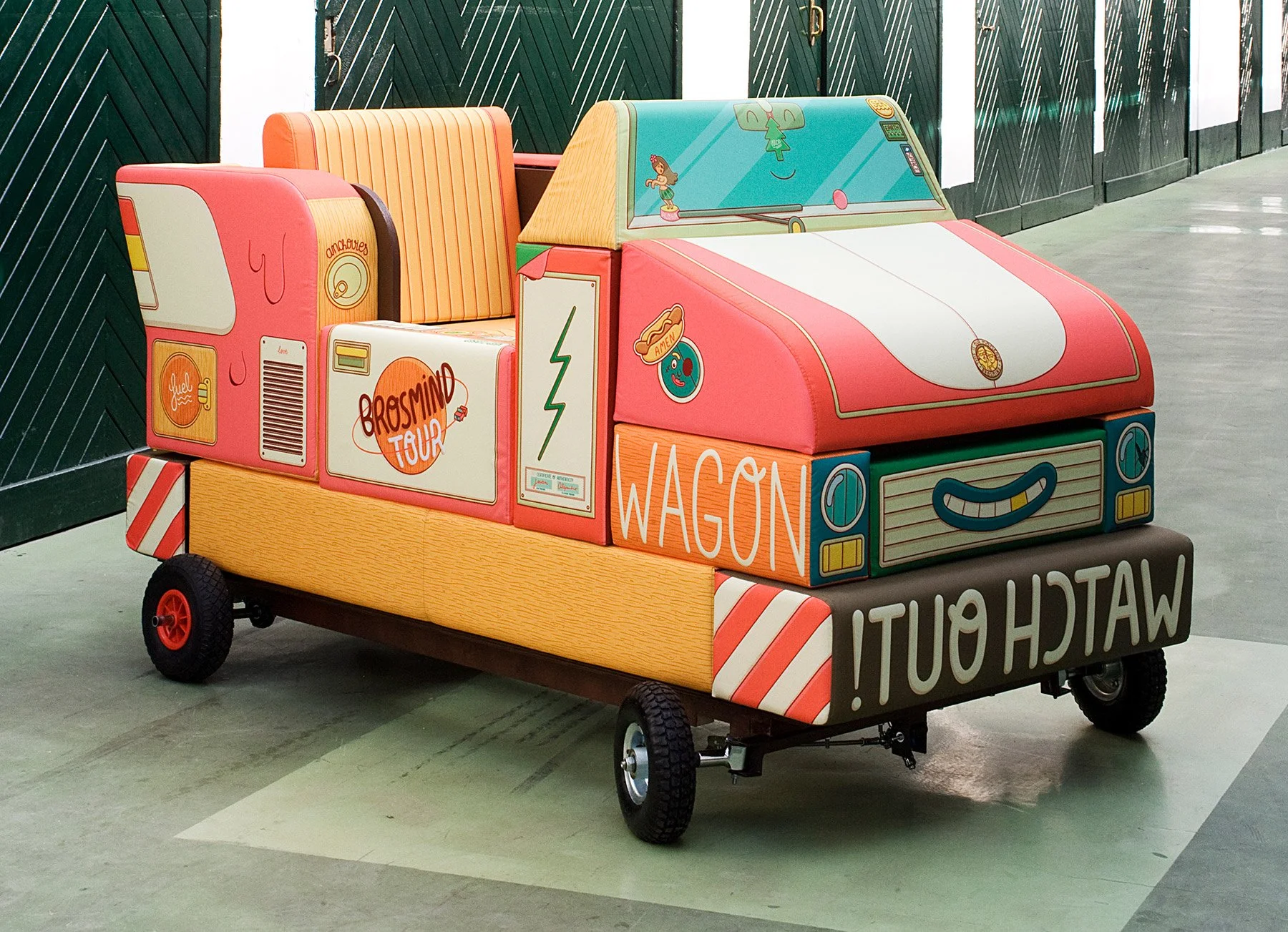 Brosmind Wagon cushion pedal car with cartoon illustrations inside an industrial warehouse gallery space. 