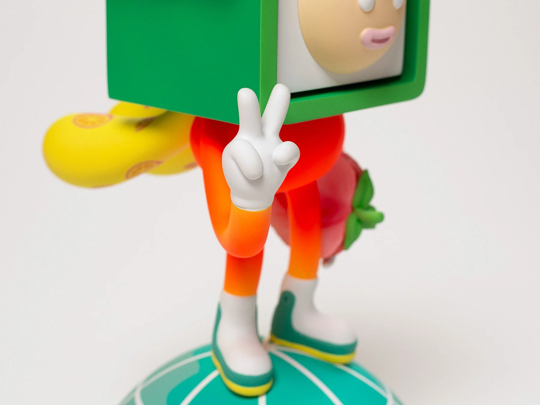 Close-up photo of the red character sculpture's hand posing with a two-finger peace sign gesture.