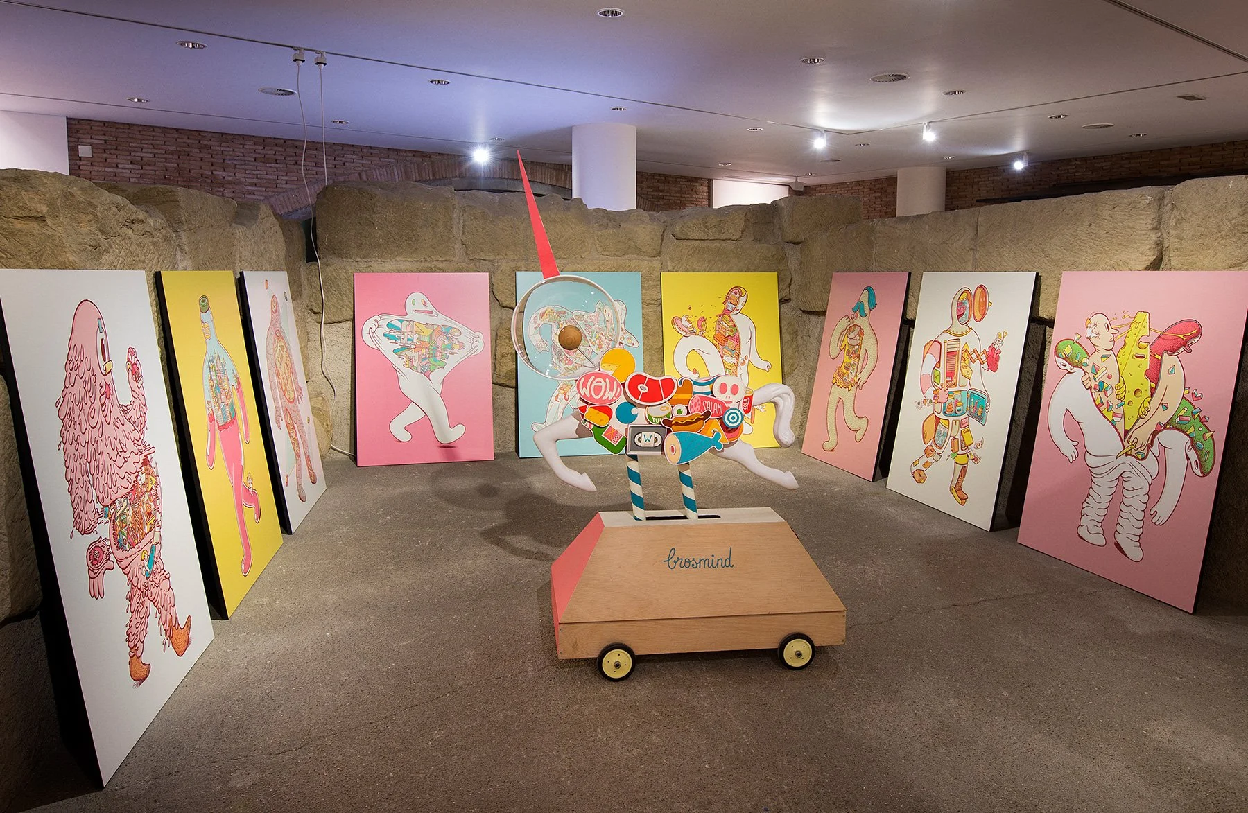 Gallery exhibition for Brosmind's What's Inside? project featuring large art prints and a mechanical ride.
