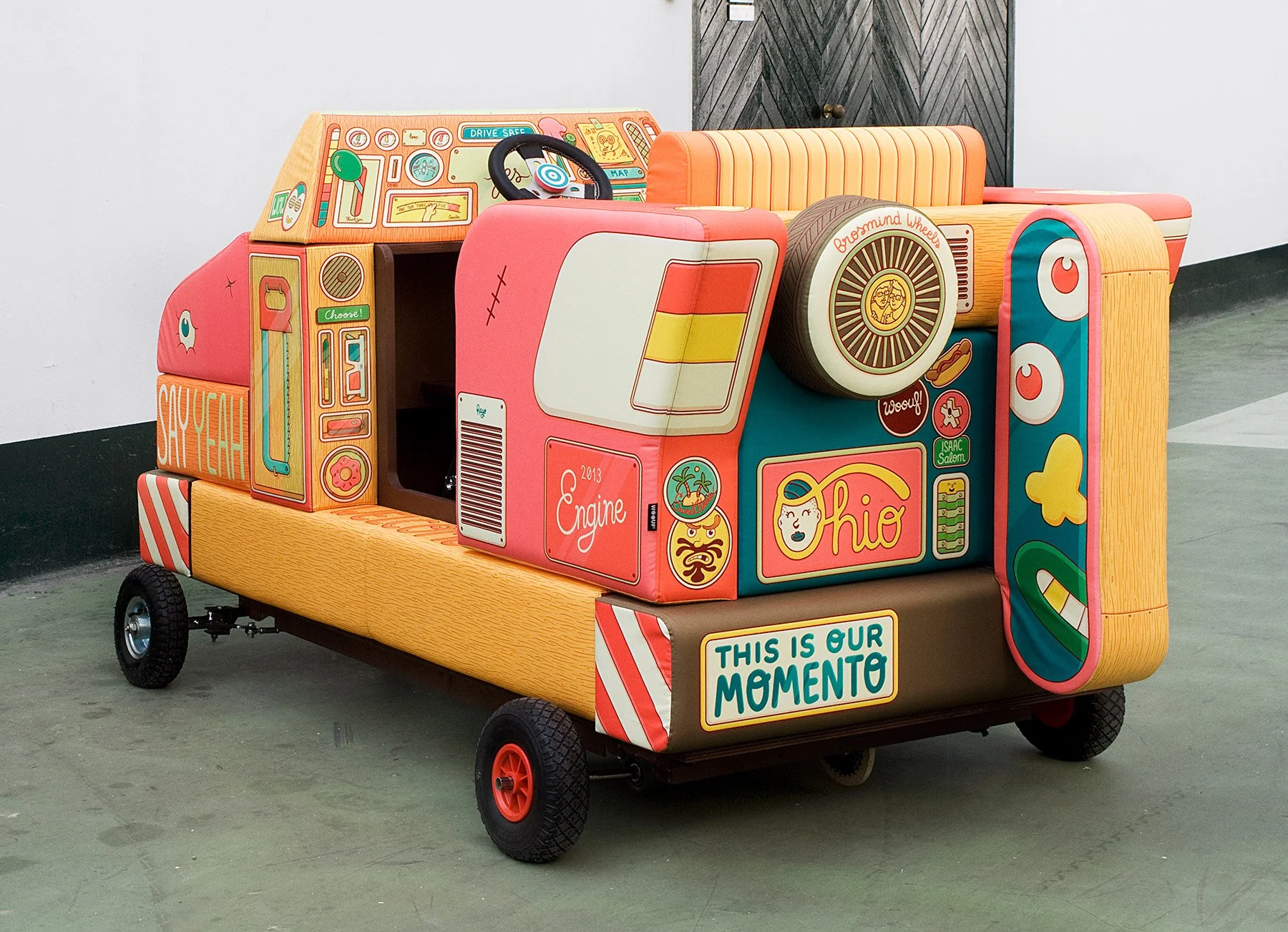 Close-up of the Brosmind Wagon steering wheel and custom illustrated cartoon dashboard radio and gauges.