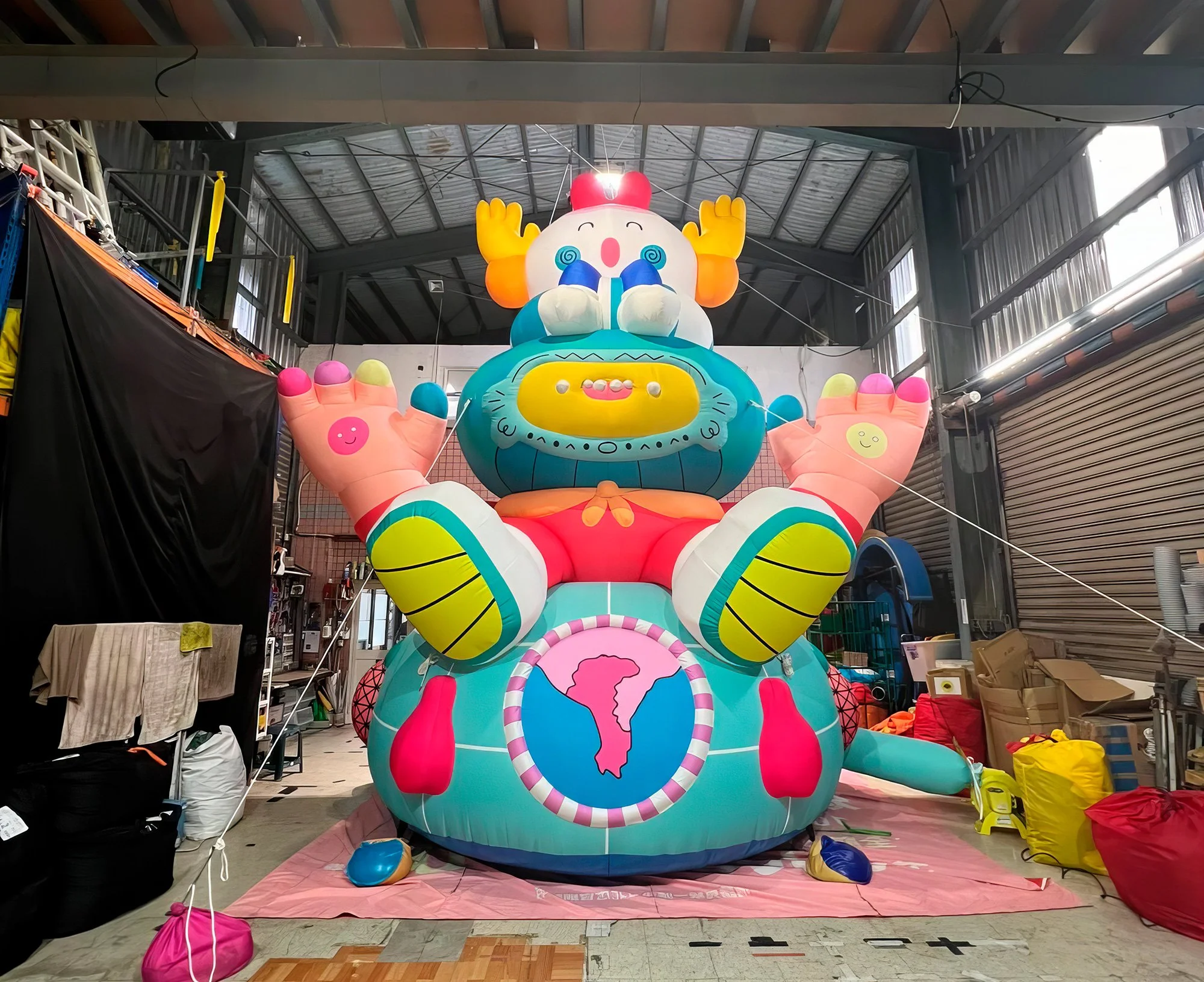 Behind-the-scenes photo of the giant Brosmind inflatable anchored with ropes inside the manufacturing factory. 