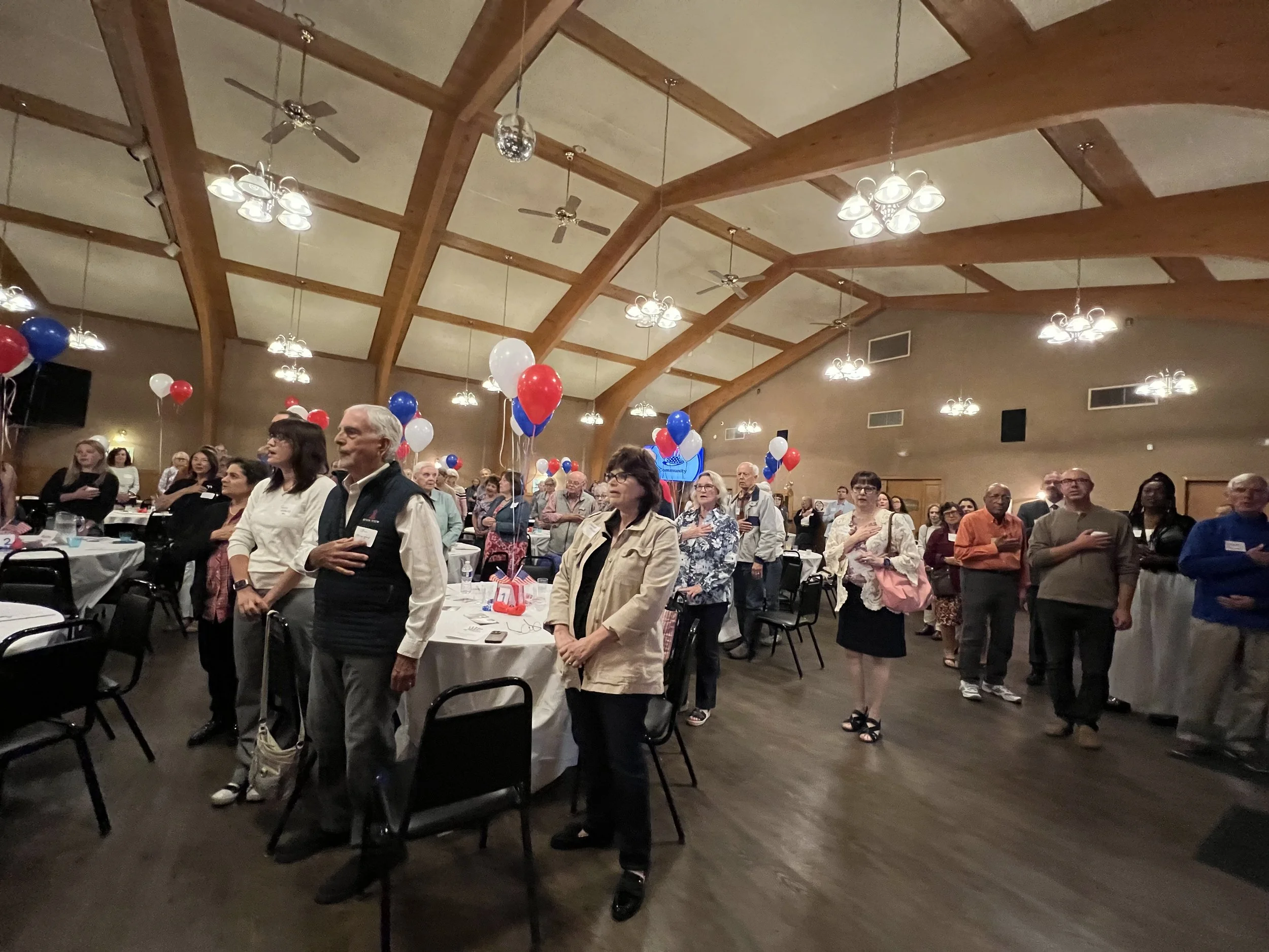 The 2025 MDTC picnic crowd puts their hands on their hearts for the national anthem. 