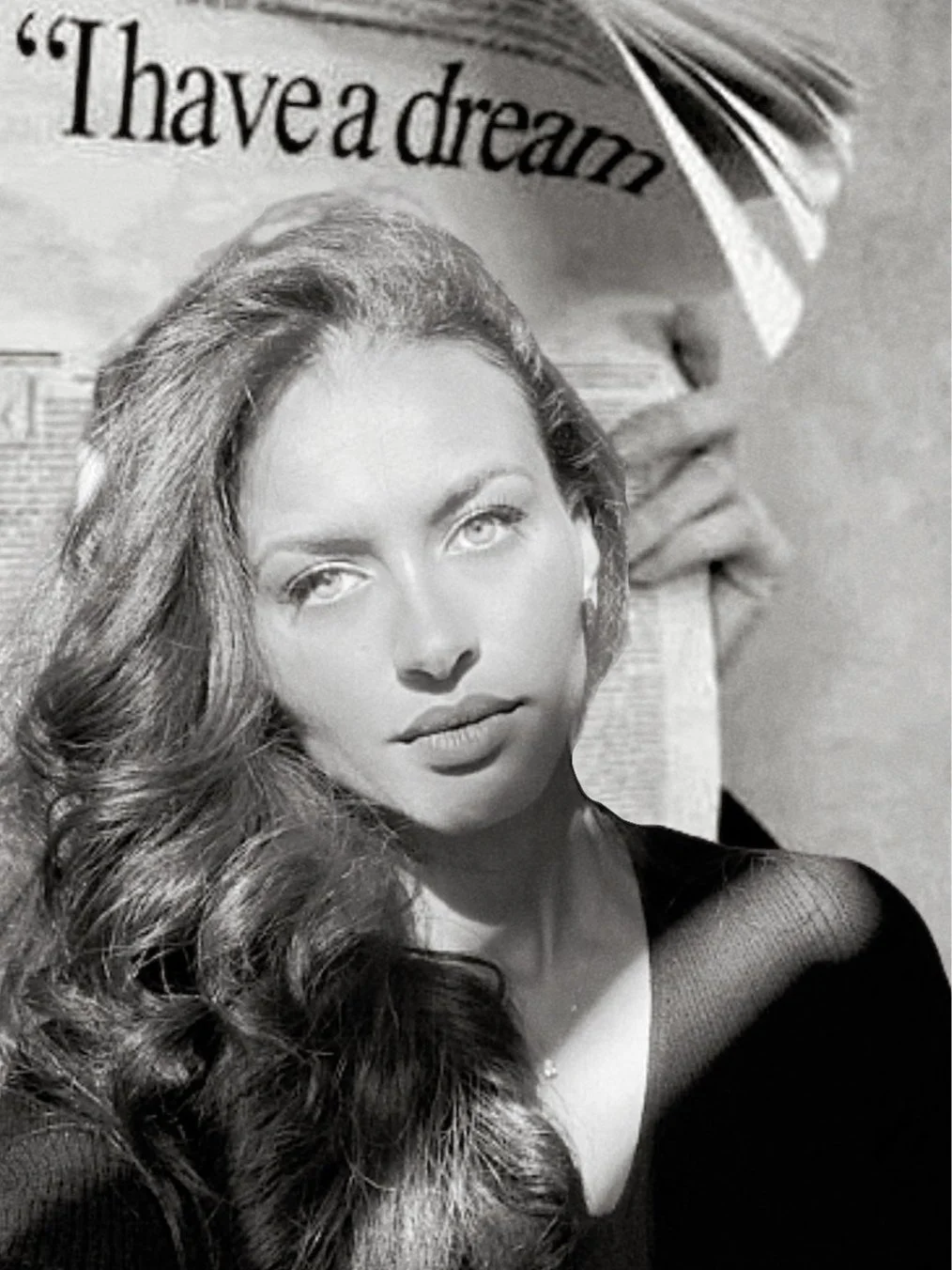 Black and white portrait of Diane GLAOUA with long wavy hair, looking at the camera, in front of a magazine with the text 'I have a dream' visible.