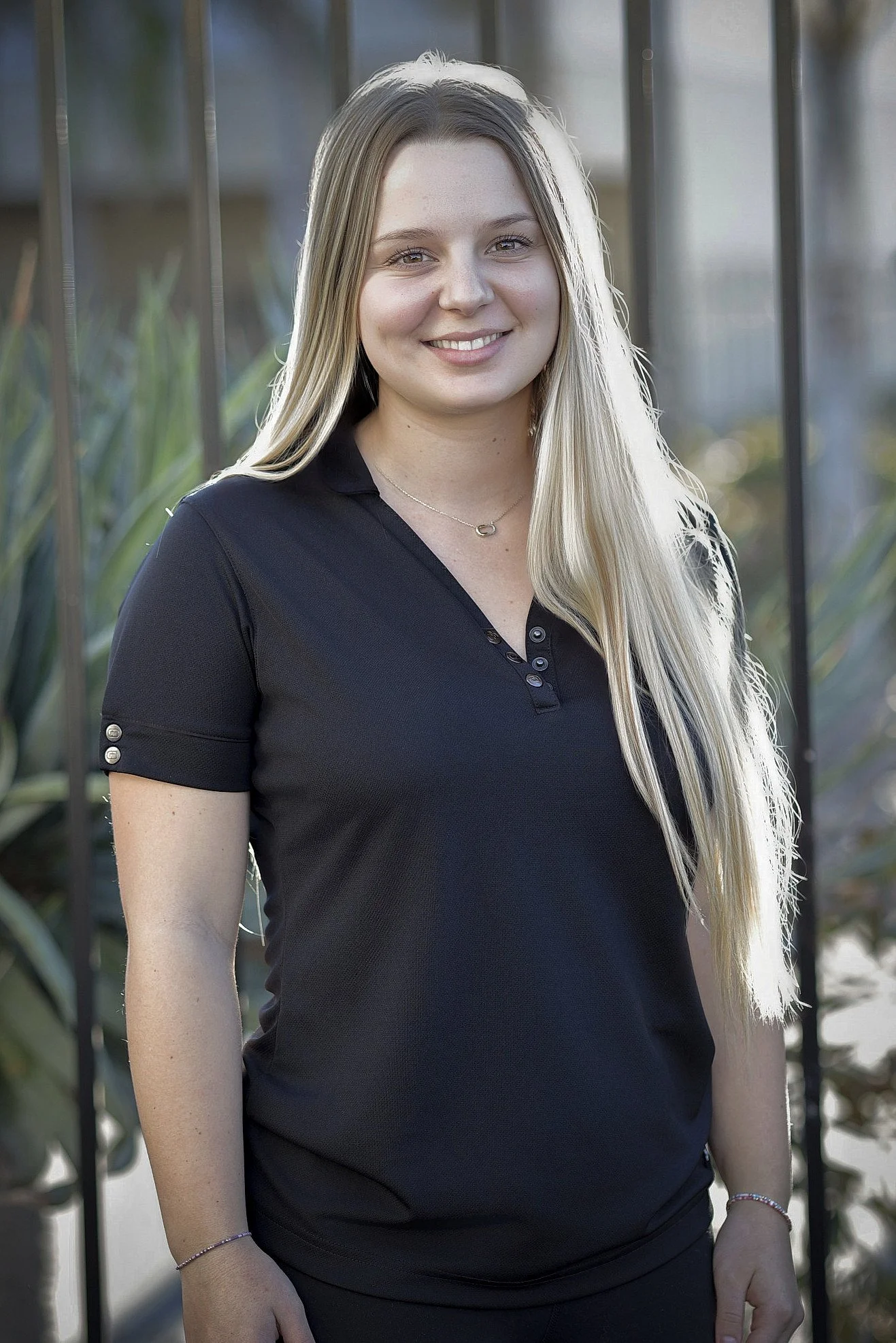 Smiling person standing in front of Hoop5 headquarters fence