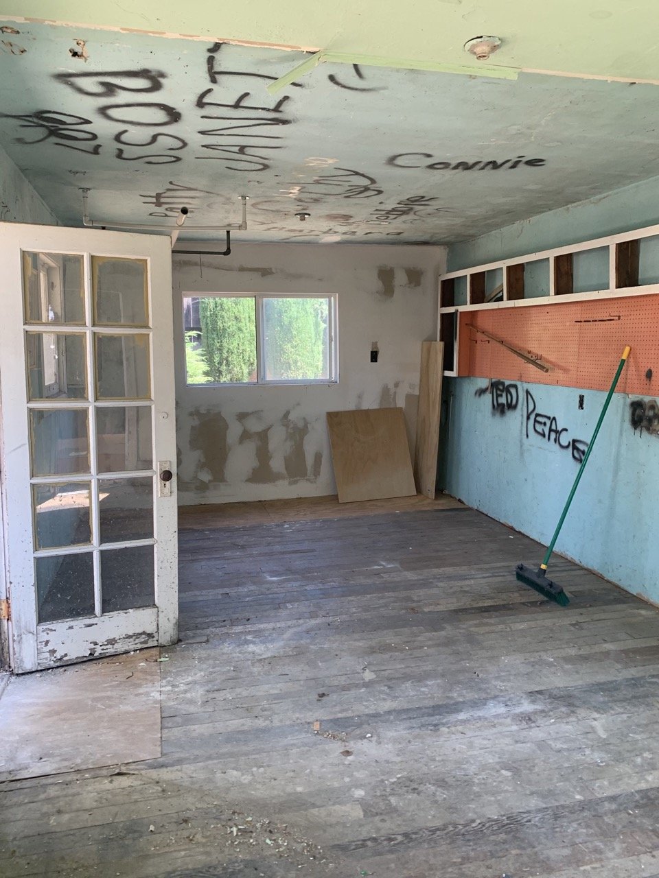 Empty room with graffiti on ceiling and walls and floating shelf. A before photo for a before and after room design make over.