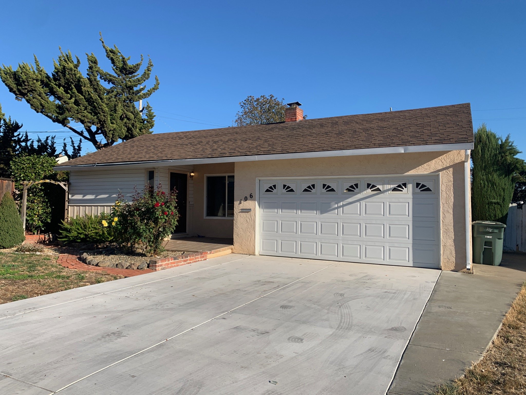 Outside of ranch style home. With white garage door and Salmon colored paint