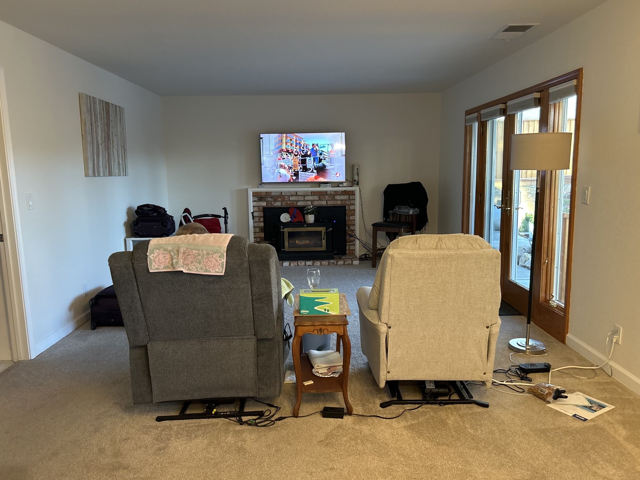 Before Style it Staging. Den sitting area with fireplace and sliding glass doors. 2 recliner chairs in the middle of the room with a table in between.