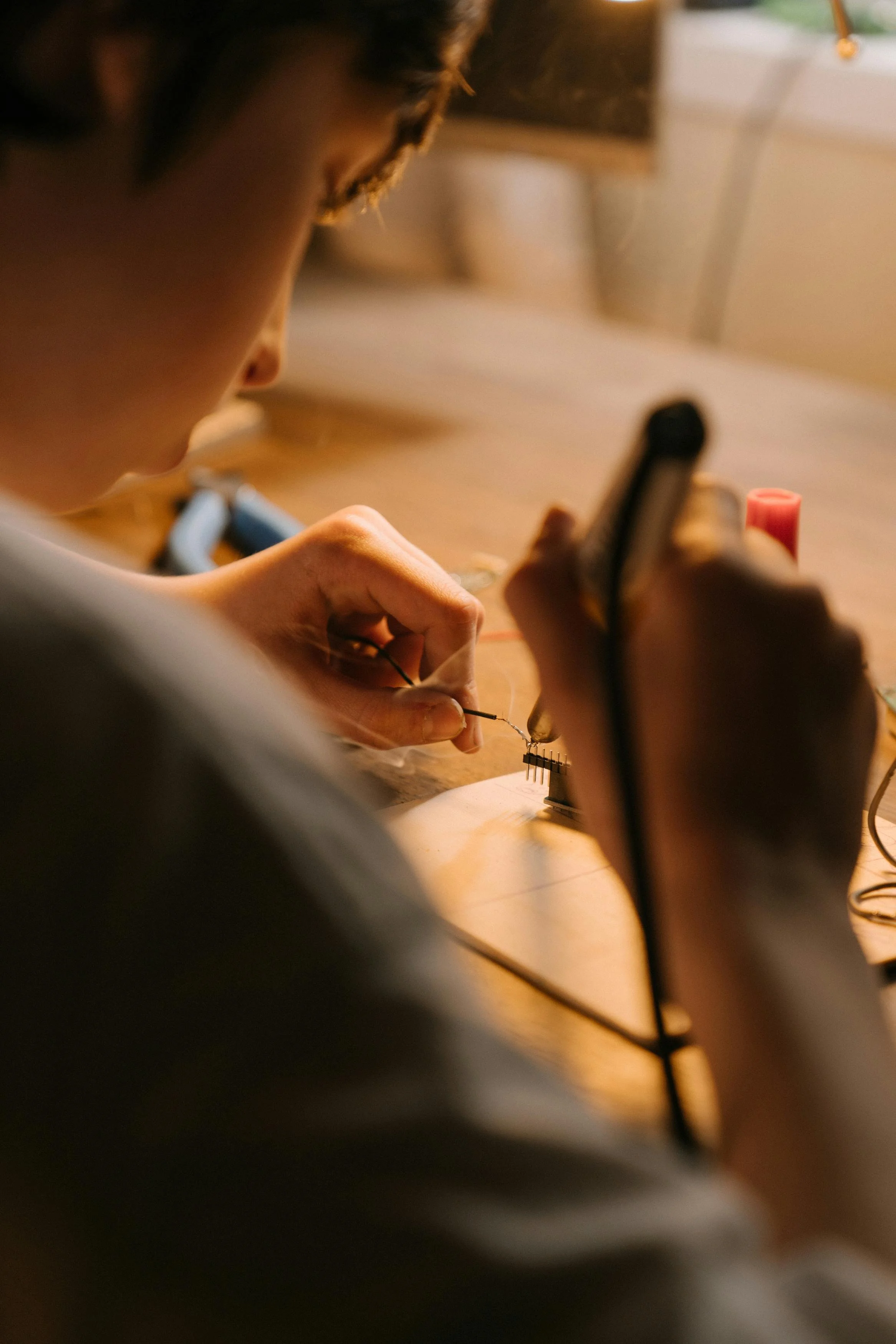 Student soldering electronic components onto a circuit board as part of a hands-on computer engineering project.