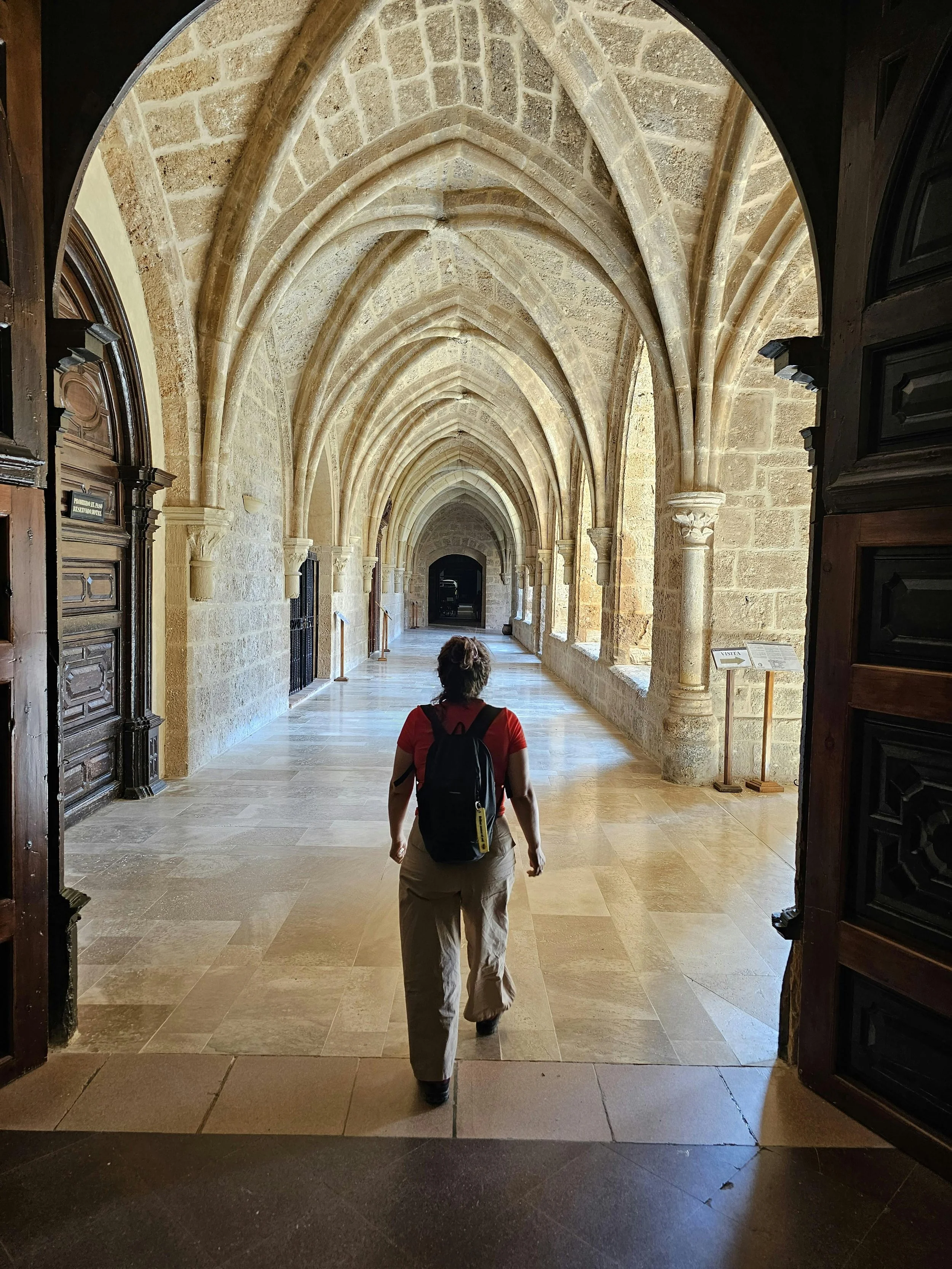 Person walking through a quiet stone hallway with arched ceilings in an academic building