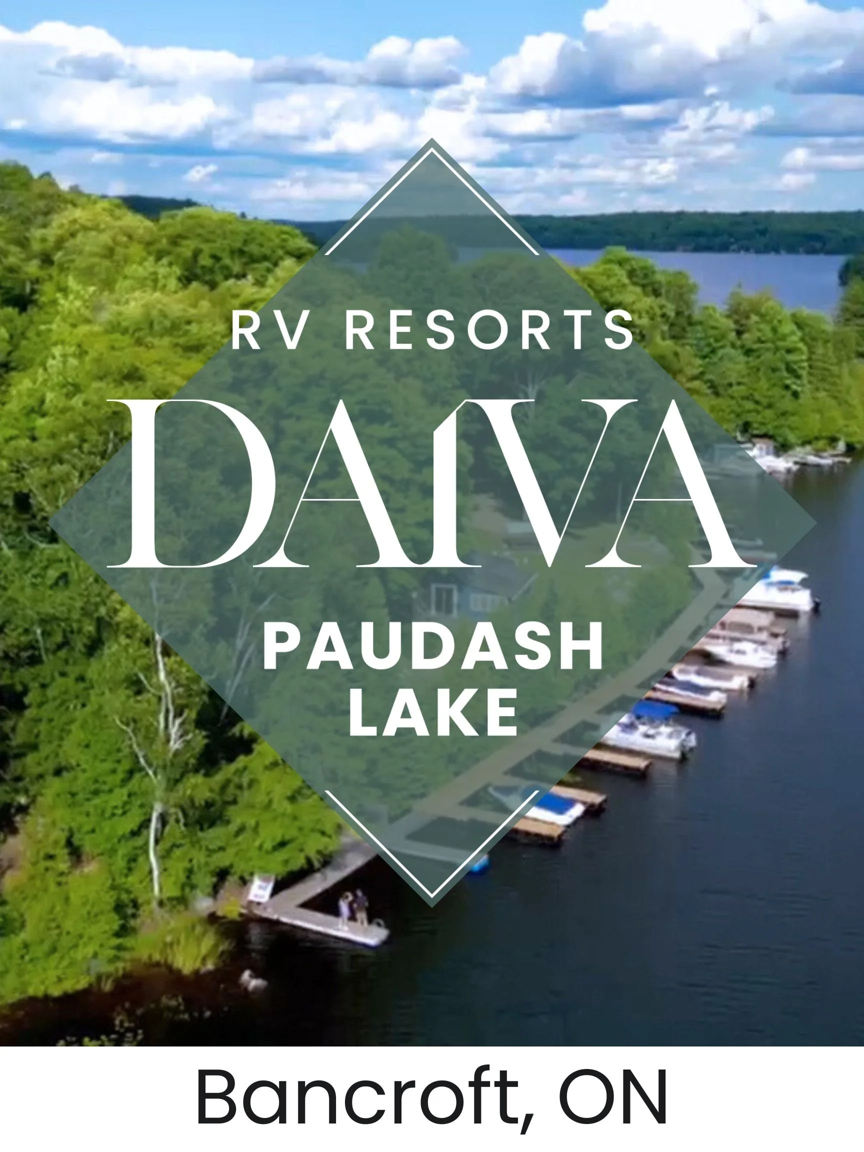 An aerial view of Paudash Lake surrounded by trees, with boats docked along the shoreline and a small house visible among the greenery, under a partly cloudy sky.