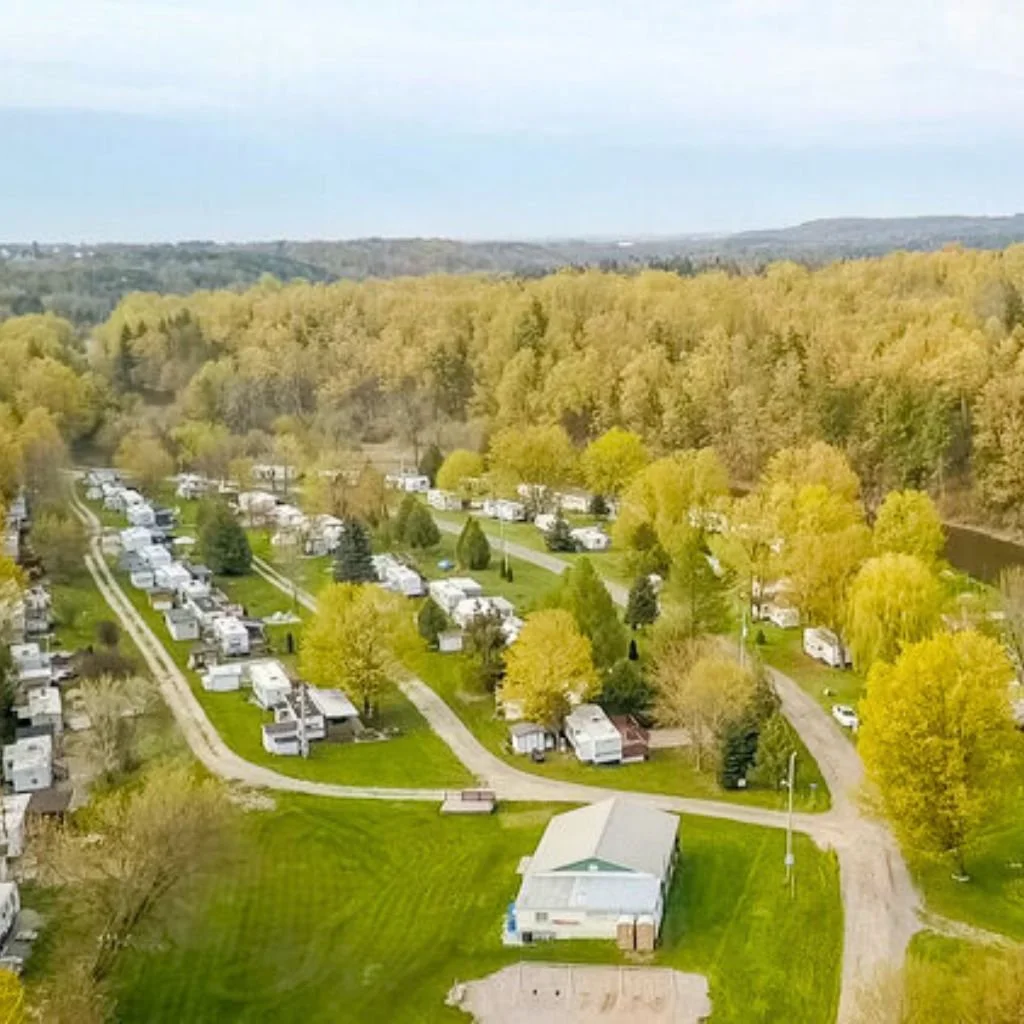 aerial view of a campground with RVs and trailers surrounded by trees