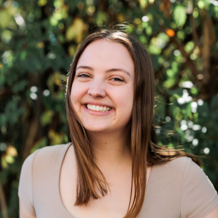 A white woman with brown hair smiling outside.