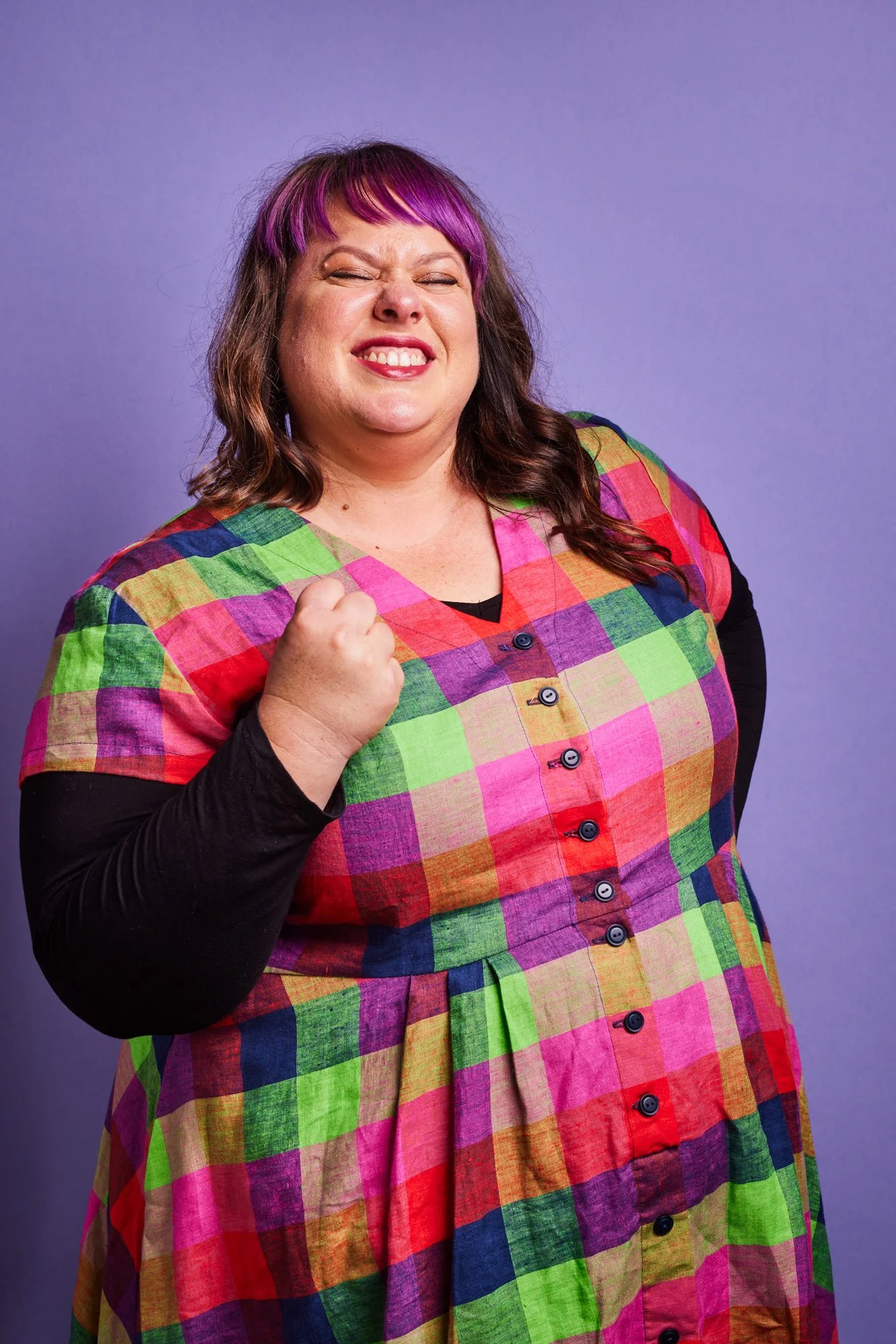 A caucasian woman wearing a bright coloured dress is celebrating something.