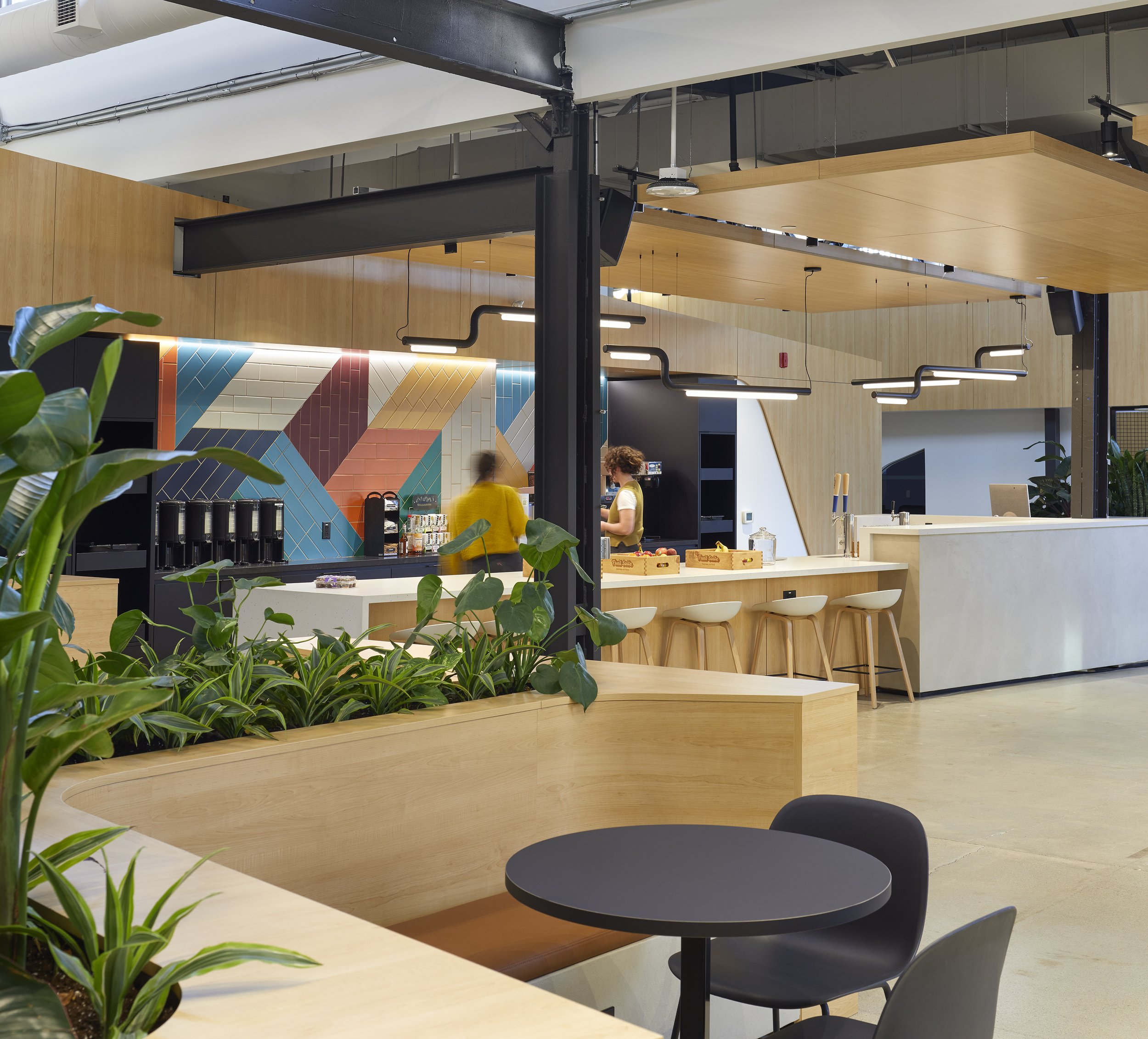 Break room with an accent wall, kitchen island, and milled benches surrounding planters.